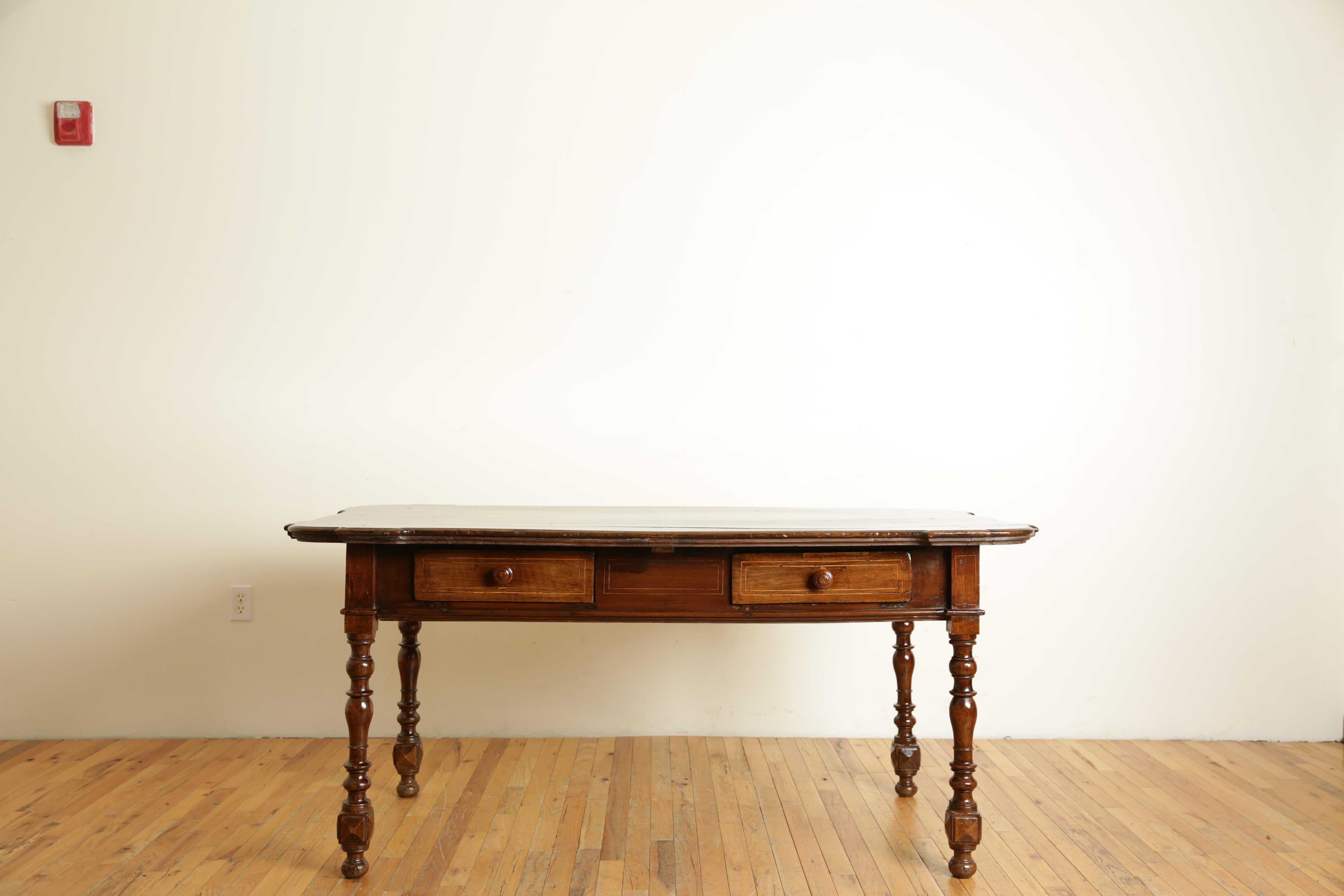 Having a rectangular top with notched corners and line inlay above a conforming case housing two drawers, raised on turned and block legs with lozenge form carvings near the feet