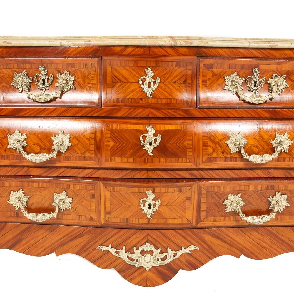 A highly-inlaid, parquetry-veneered, Italian three-drawer ‘bombe’ commode, embellished with finely-cast gilt mounts and a shaped marble top with complex edge, circa 1920.

 