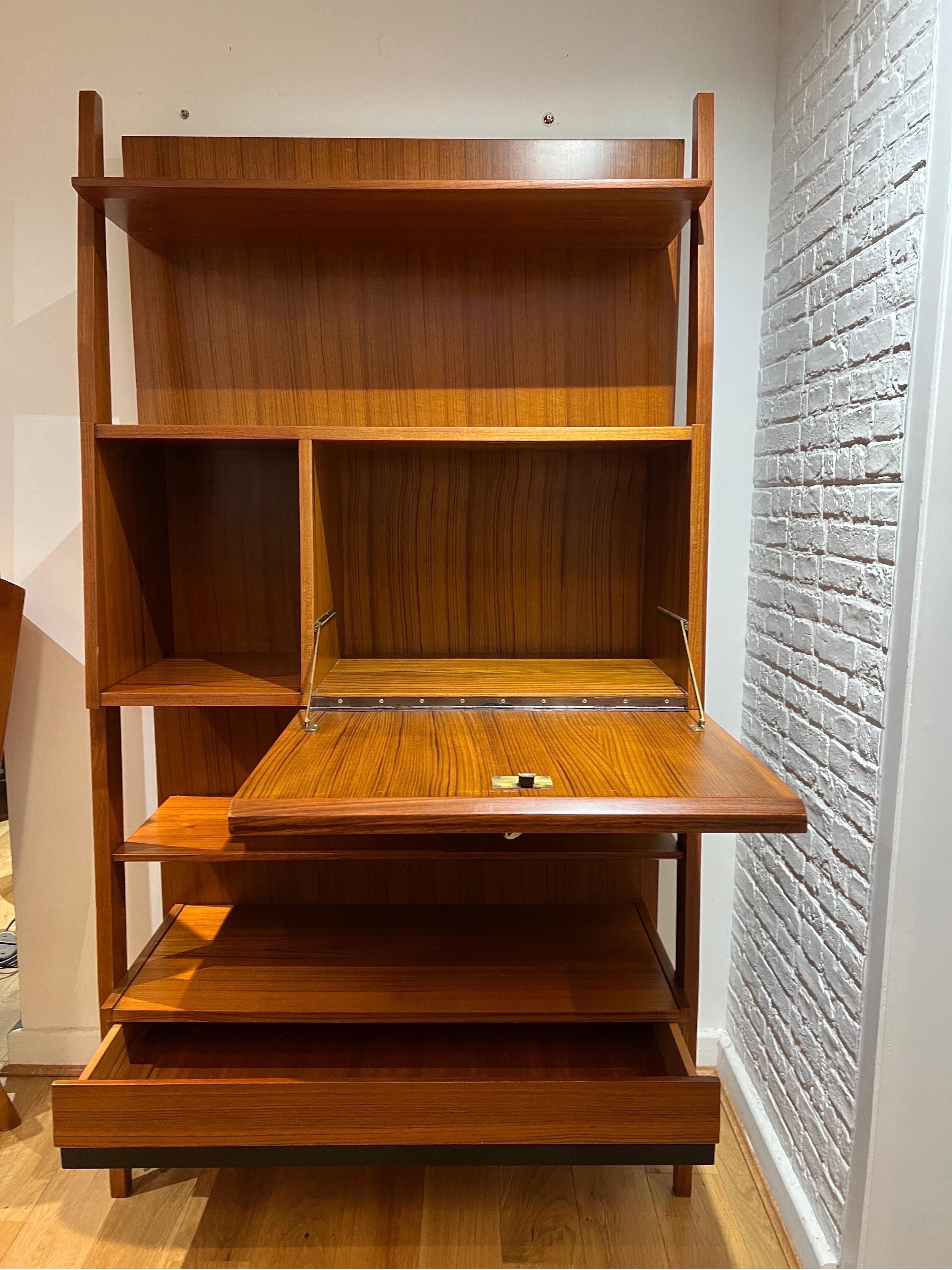 An Italian freestanding cherrywood bookcase consisting of 5 shelves and a lockable pull door that reveals a barware storage section. At the bottom a concealed single file drawer. The cabinet is supported on both sides by a full length