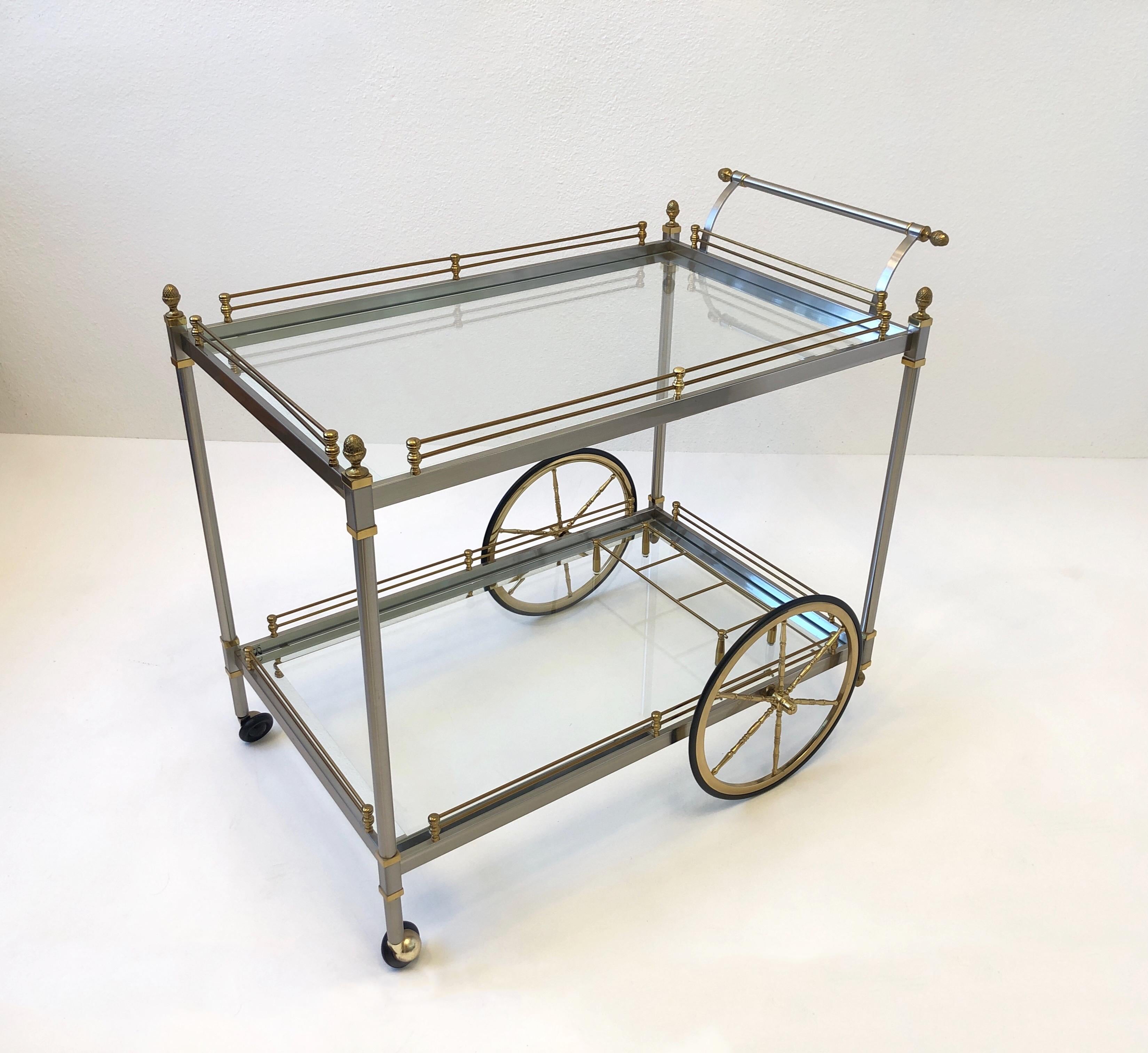 Glamorous 1970’s Italian two tier bar cart. 
Constructed of brass and brushed steel with mirror framed glass shelves. 
This is in beautiful vintage condition. 
Measurements: 34.5” Wide, 22” Deep, 30” High.