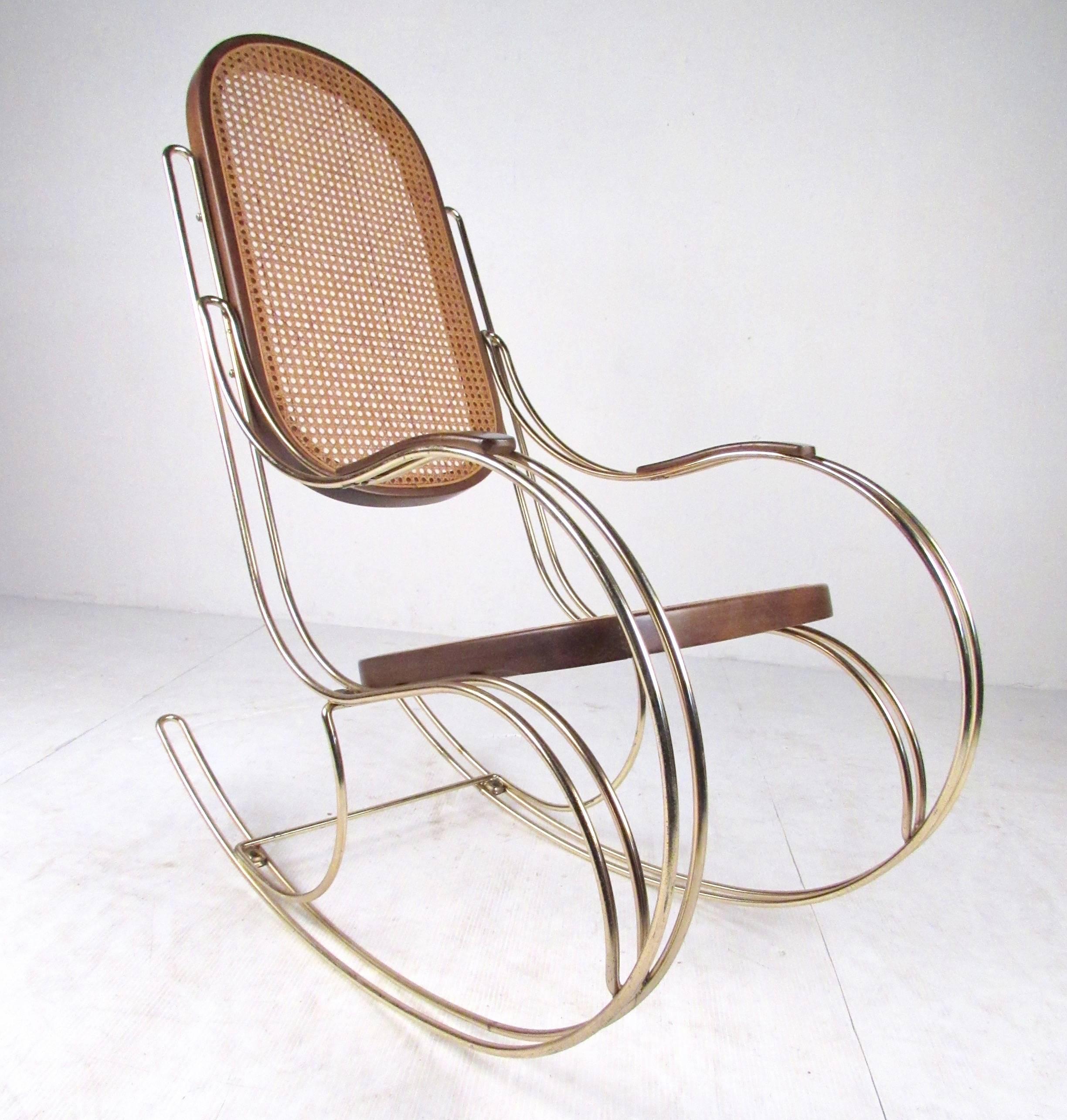 Cette jolie chaise à bascule inspirée de la Thonet, avec sa structure en laiton et son assise en rotin, allie une esthétique traditionnelle et moderne compatible avec tous les décors. Veuillez confirmer la localisation de l'article (NY ou NJ) auprès