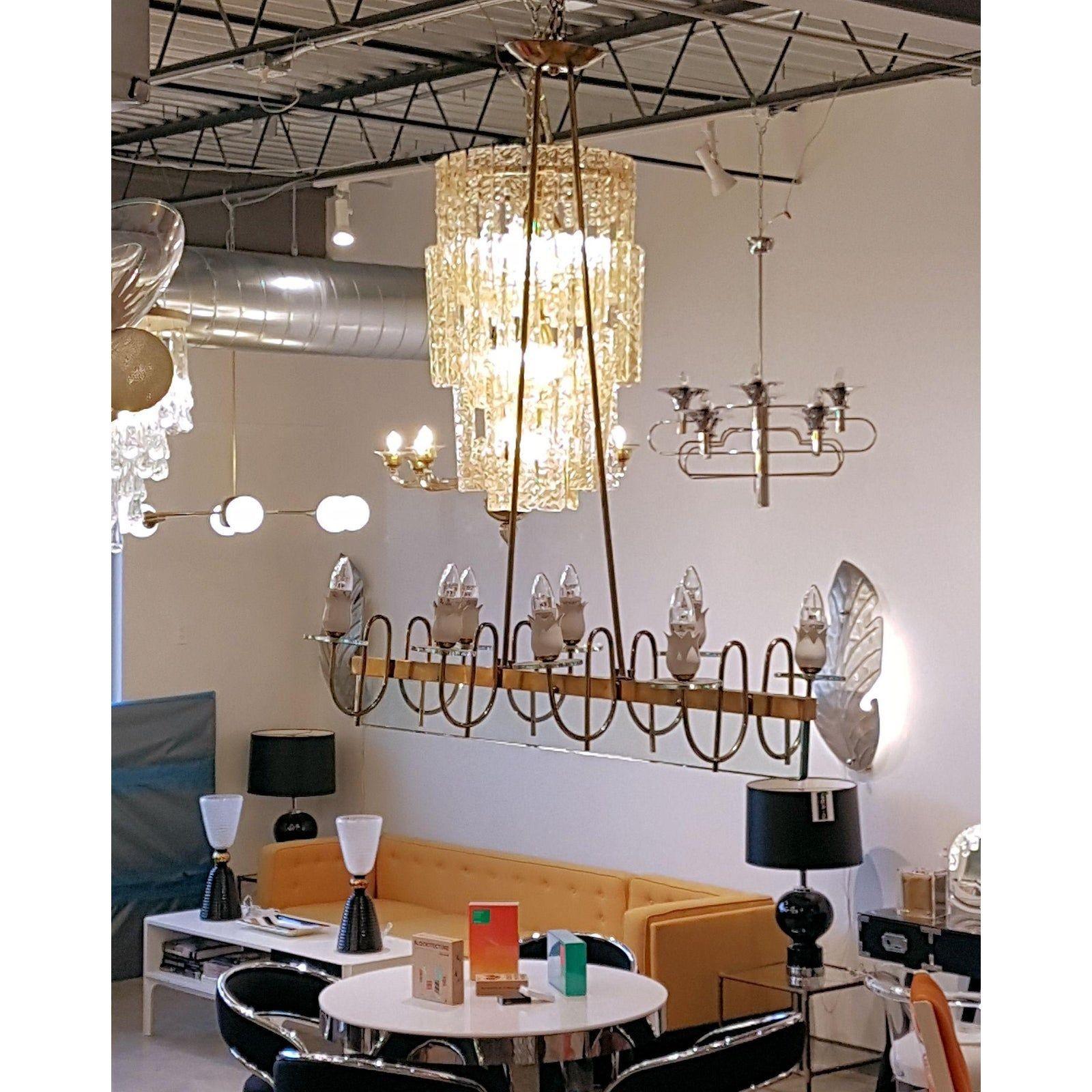 Mid century modern, Fontana Arte style elongated chandelier; with light green clear glass & brass mounts.
The vintage chandelier has eight lights, nested in an enameled white floral bobeches.
It's rewired for the US.
The chandelier can be adjusted