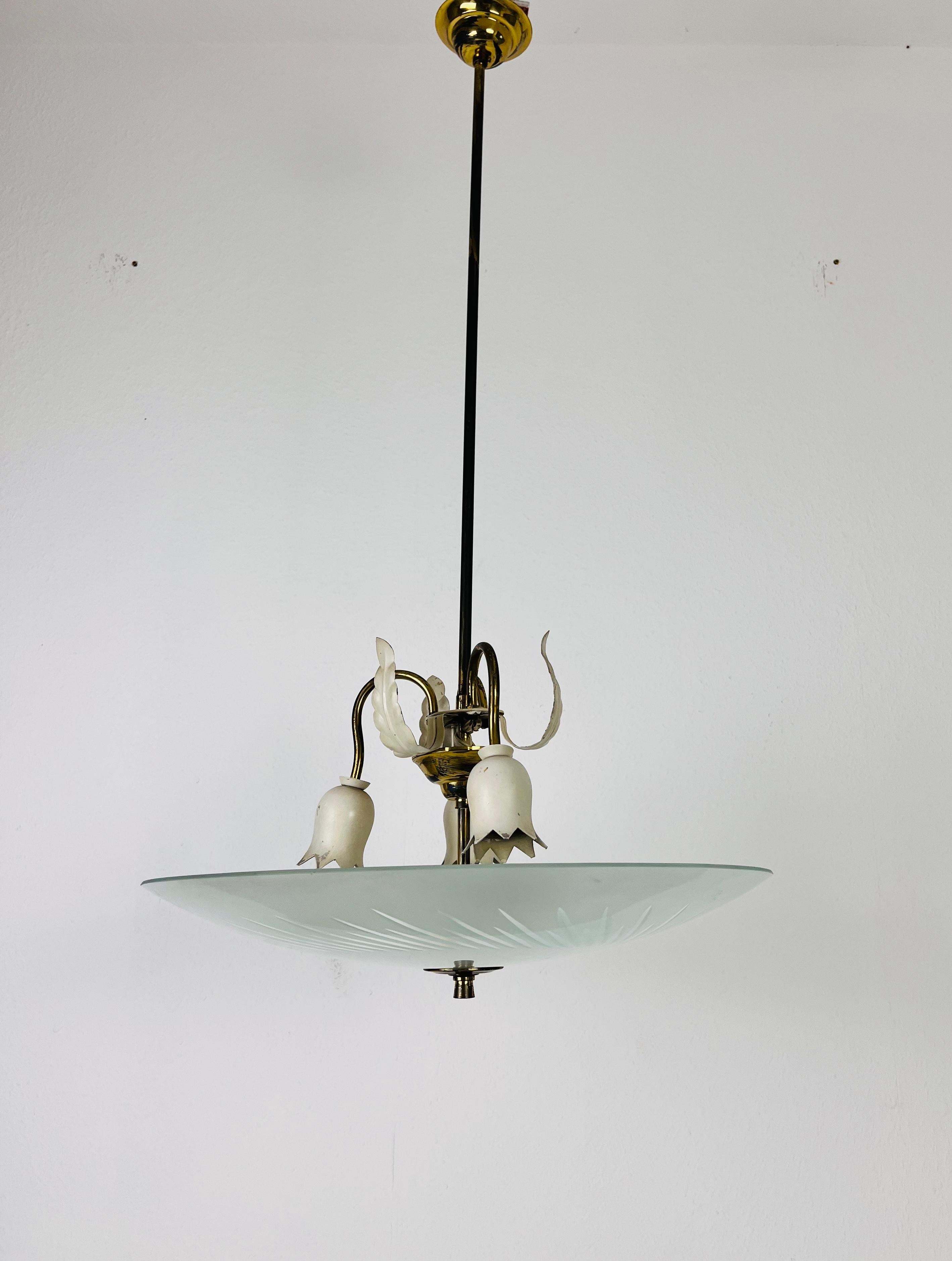 A midcentury chandelier made in Italy in the 1950s. It is fascinating with its unique saucer shape and wonderful brass elements.

The light requires 3 E27 (US E26) light bulbs under the glass element. Good vintage condition.

Free worldwide