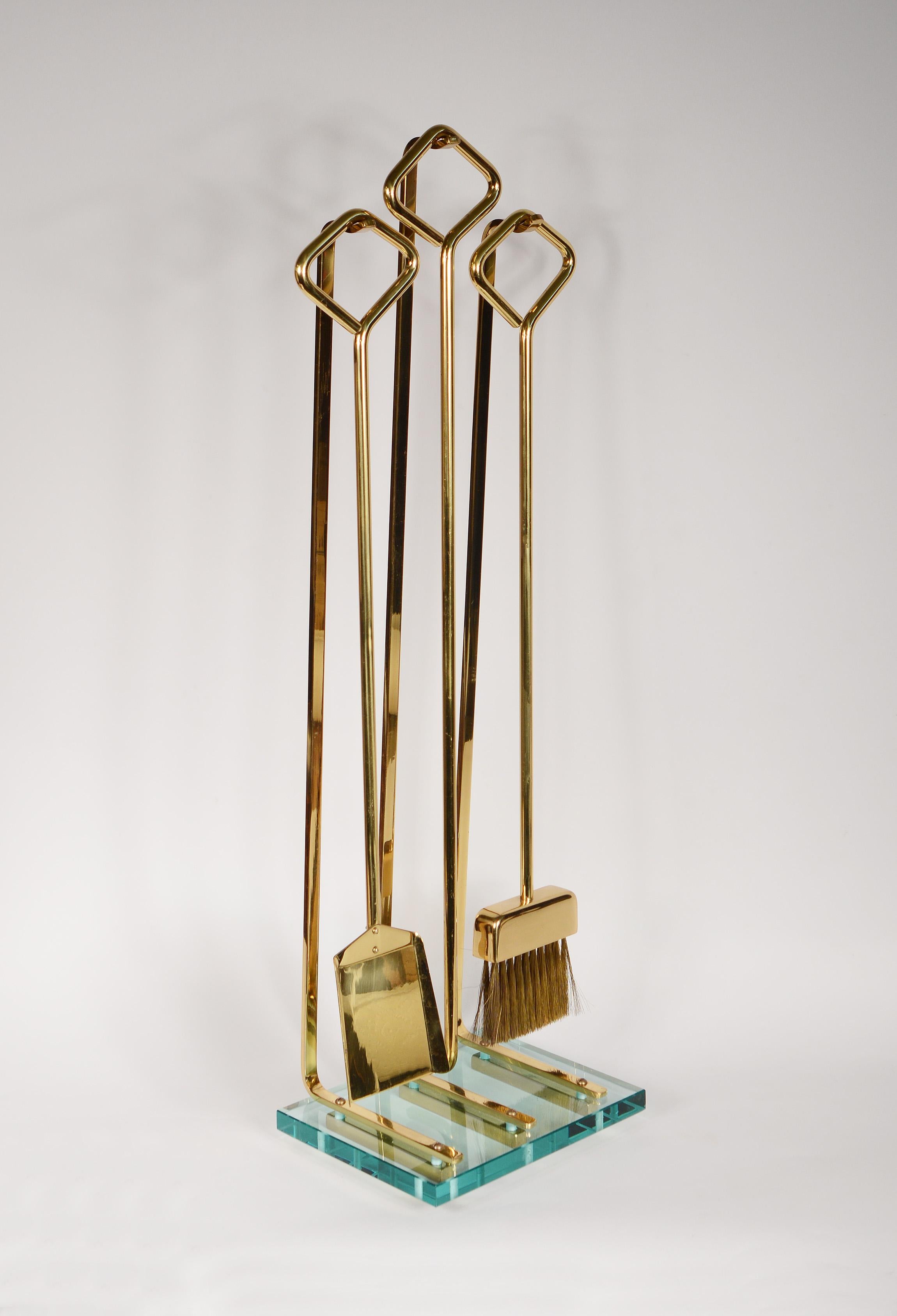 These mid century Italian fireplace tools are often attributed to Fontana Arte. While Fontana Arte is not the maker of this set the quality is on an equal level. The base is 3/4 glass with brass feet and brass rods holding the tools. This set has a