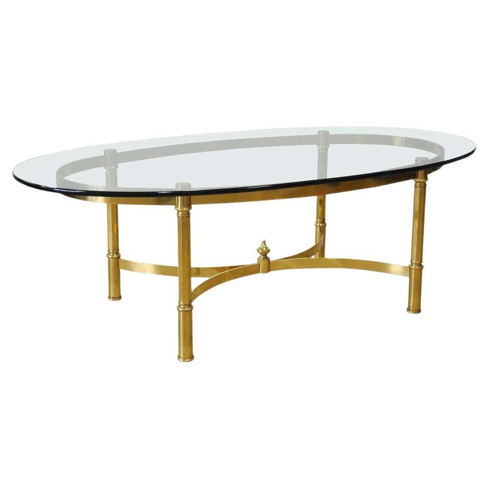 Tavolino da caffè o da cocktail degli anni '60, di forma ovale e con struttura in ottone. Base a forma di pista con colonne sfaccettate e supporti a barella curvi. La superficie del vetro ha uno smusso arrotondato e una forma ellittica o a pista.