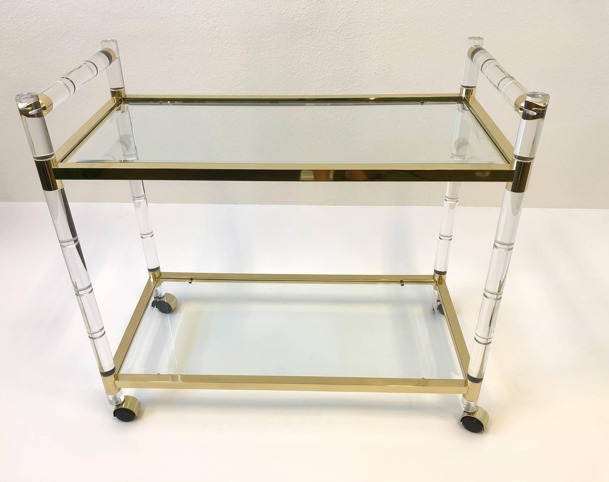 A glamorous 1970s Italian polish brass and stylized bamboo motif clear Lucite with bevelled glass shelves inserts. The cart has been newly totally restored. 

Dimensions: 33.5” high, 18.5 deep and 36.75 wide.