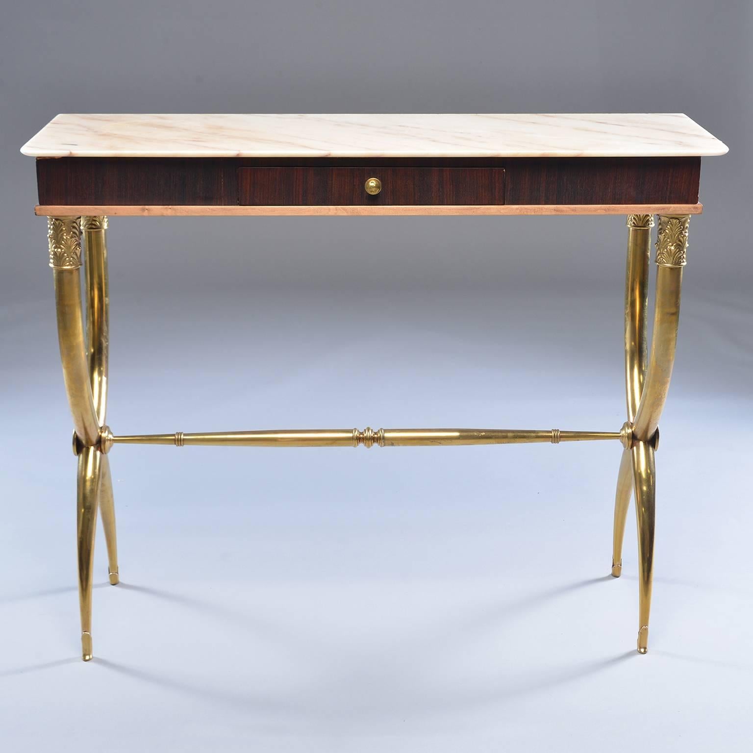 Italian neoclassical style console has brass base with X-form tapered legs embellished with acanthus leaf detail at top, tapered stretcher, wood table with single centre drawer and creamy marble top with pale apricot veins and streaks, circa 1960s.