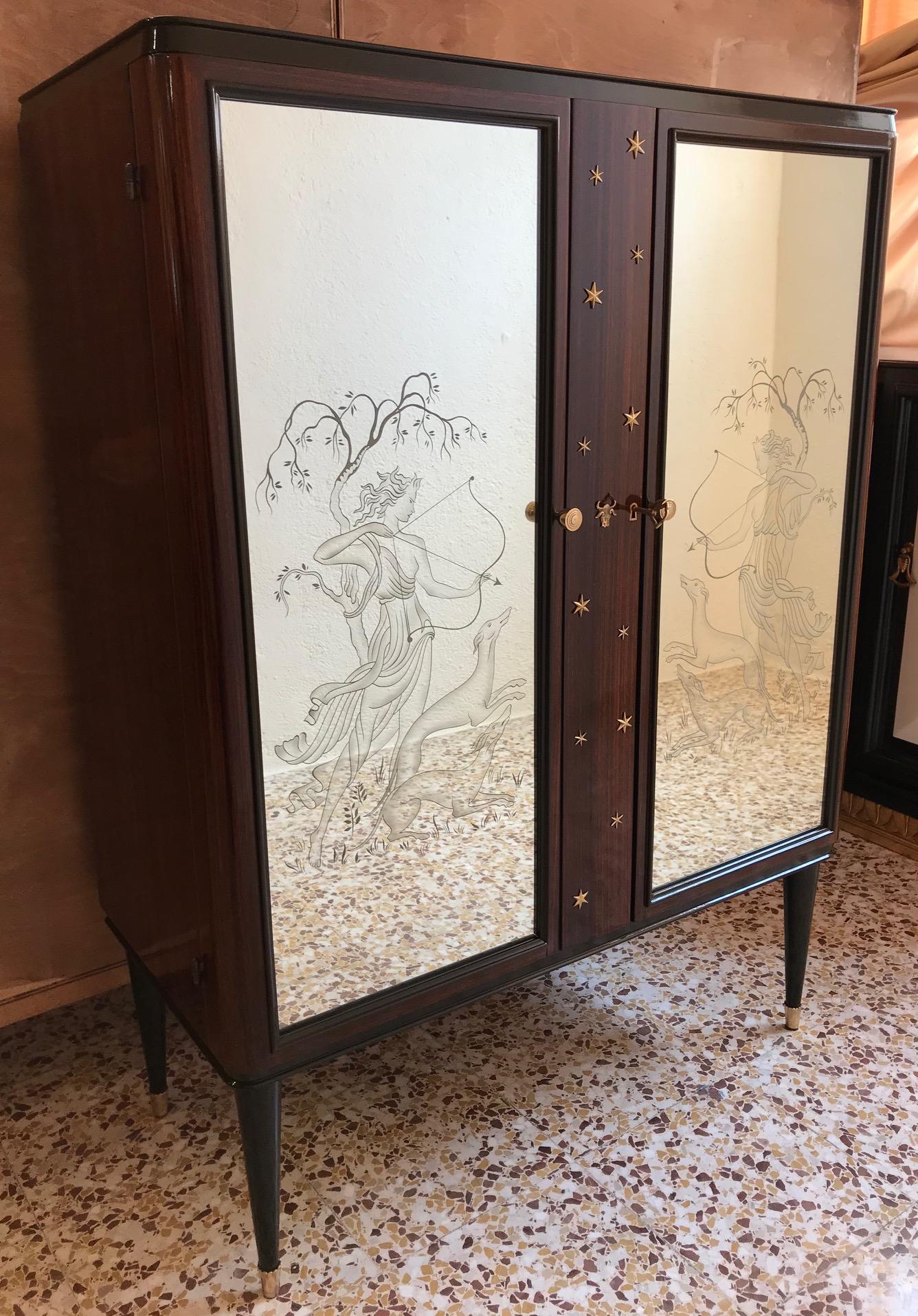 This unique bar cabinet was produced in Italy in the 40s attributed to Osvaldo Borsani.
The two engraved and sanded mirrors represent Diana 'the hunter'.
The central part is covered with stars and a brass bull.
The inside is covered with