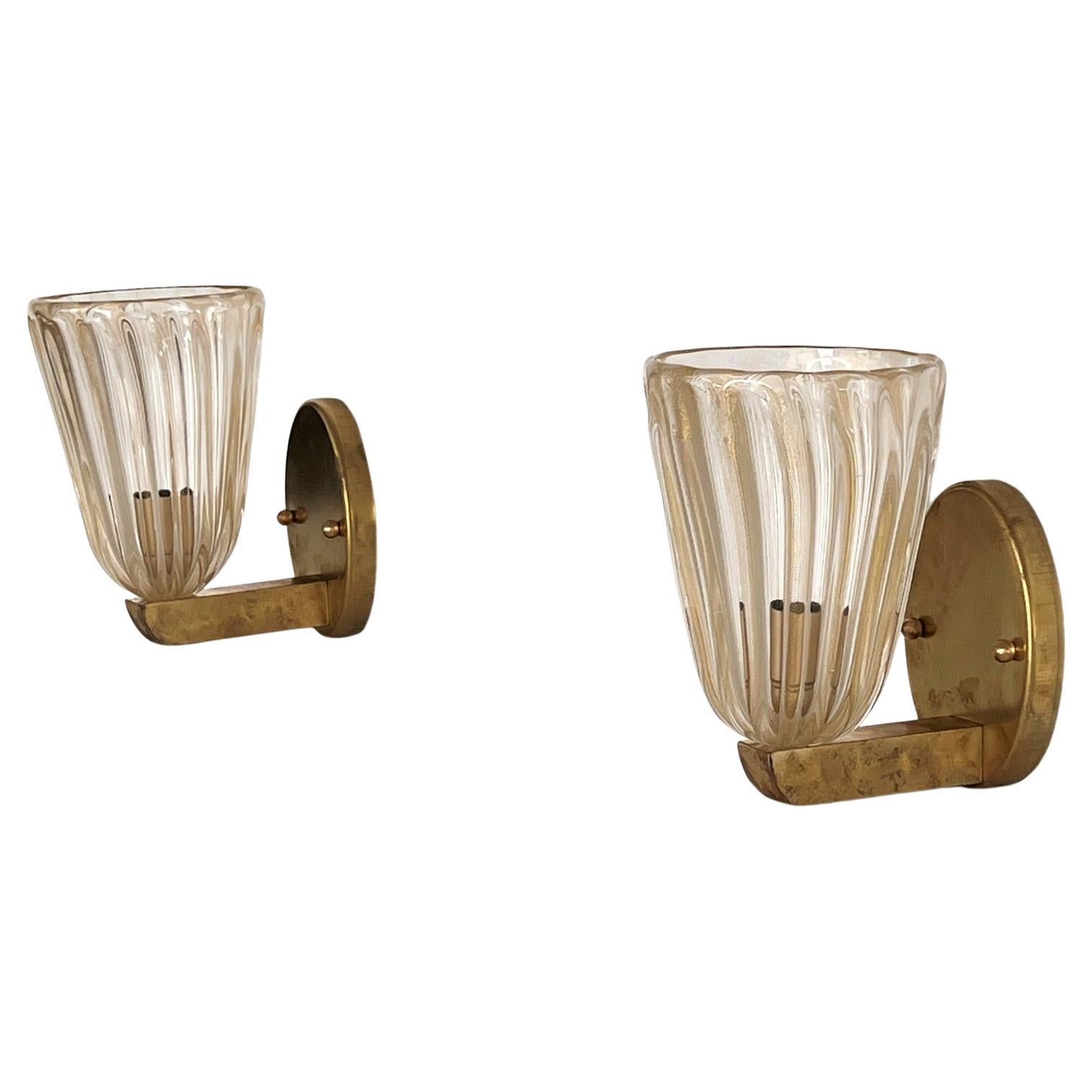 Beautiful set of two gorgeous brass wall lamps made of strong brass base and transparent Murano glasses with golden shimmer/glitter inside the glass. Art Deco style.
The beautiful hand-crafted glasses have a slight wave shape, please look carefully