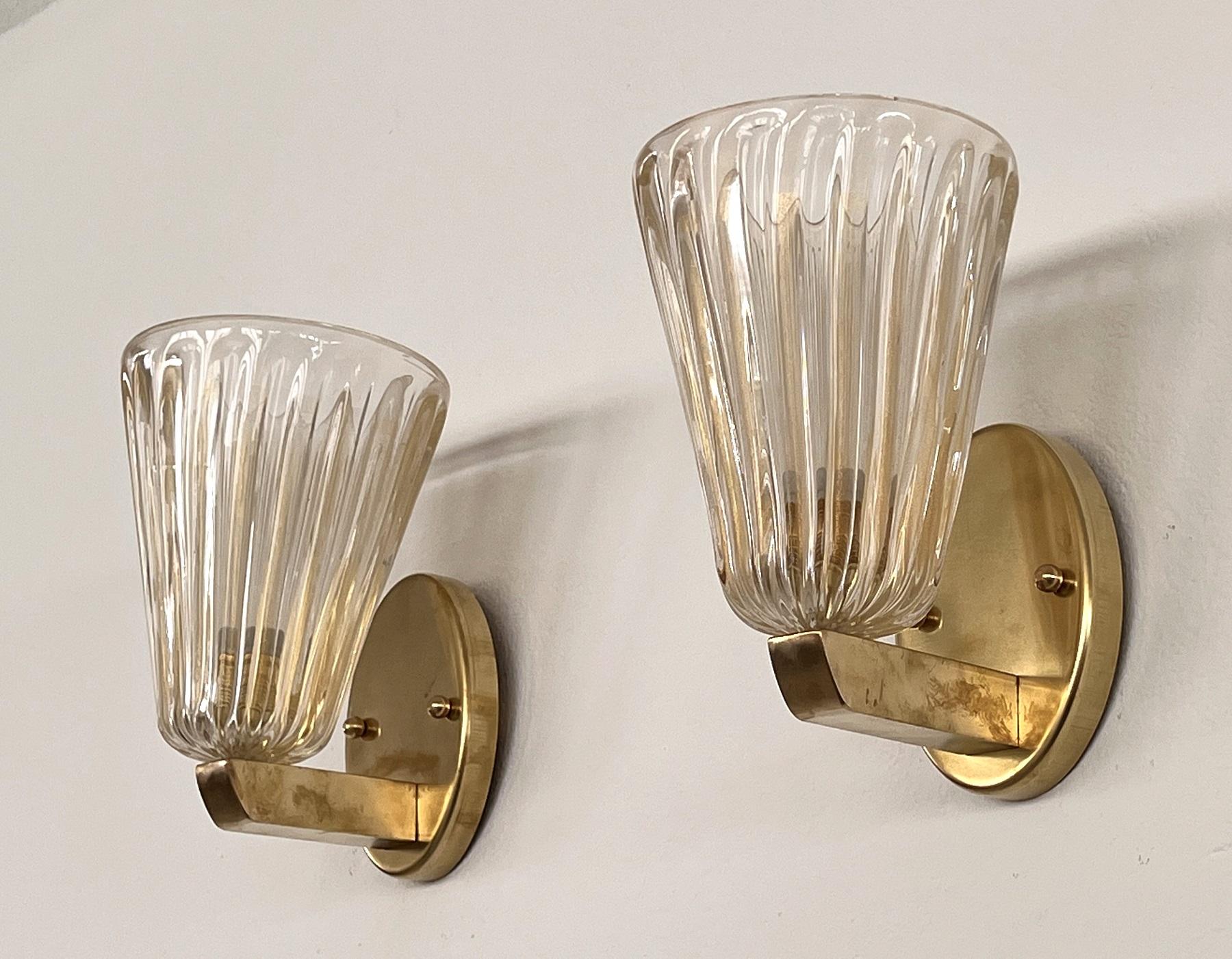 Beautiful set of two gorgeous brass wall lamps made of strong brass base and transparent Murano glasses with golden shimmer/glitter inside the glass. Art Deco style.
The beautiful hand-crafted glasses have a slight wave shape, please look carefully