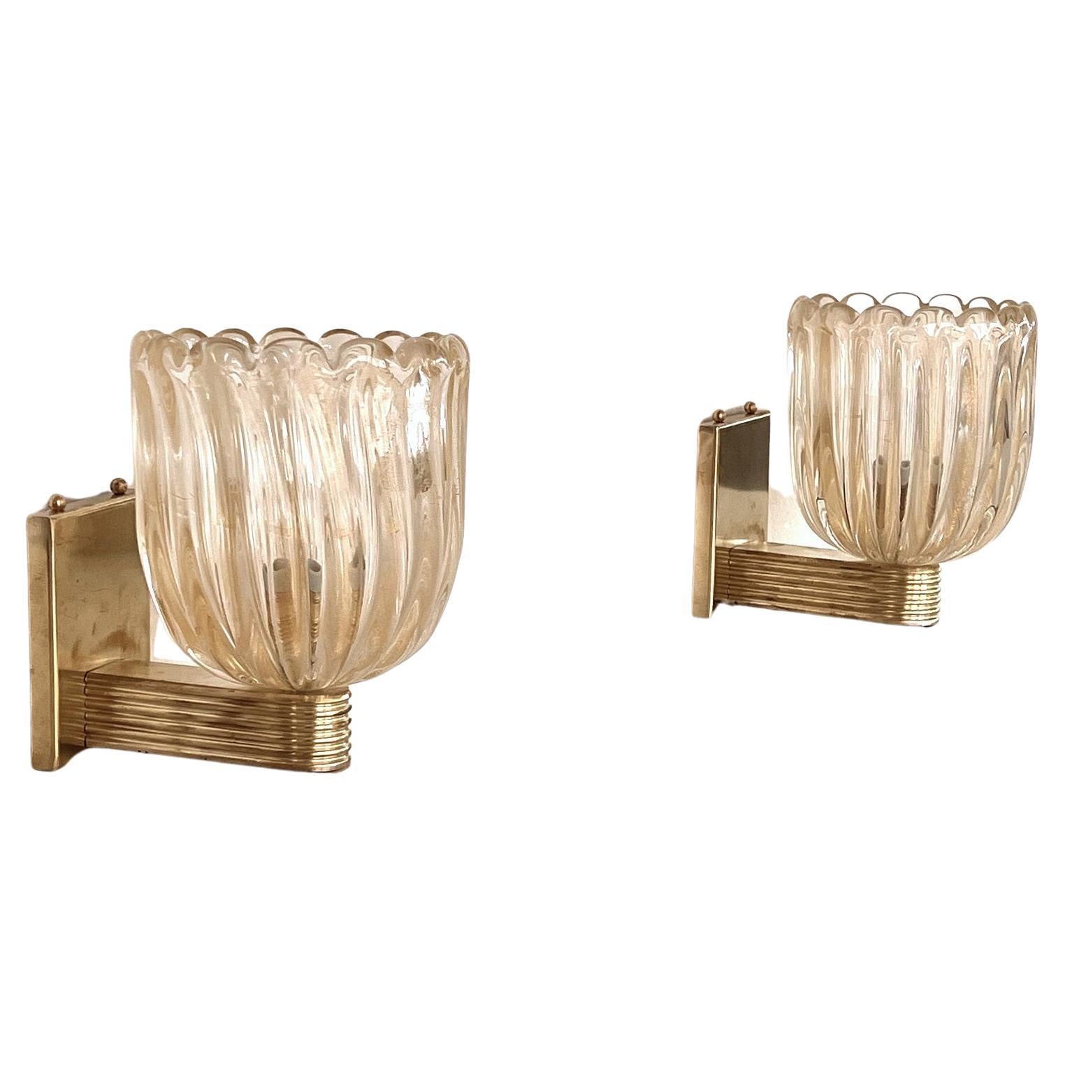 Beautiful set of two gorgeous wall lamps made of strong light amber/transparent thick Murano glasses with golden shimmer/glitter inside the glass and strong brass base. Art Deco style.
The beautiful hand-crafted glasses have a slight wave shape,