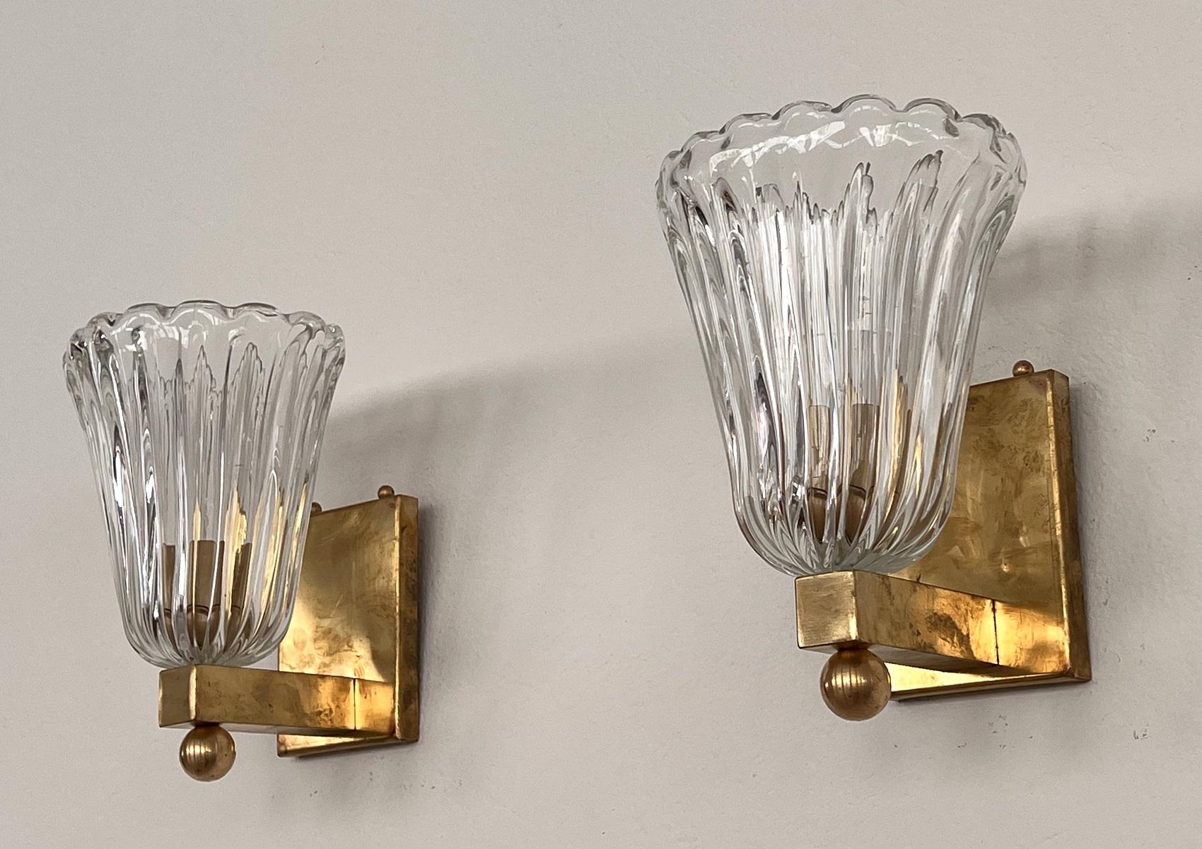 Beautiful set of two gorgeous wall lamps made of strong transparent thick Murano glasses and strong brass base. Art Deco style. Beautiful with the brass ball mounted at the bottom of the lamp
The beautiful hand-crafted glasses have a slight wave