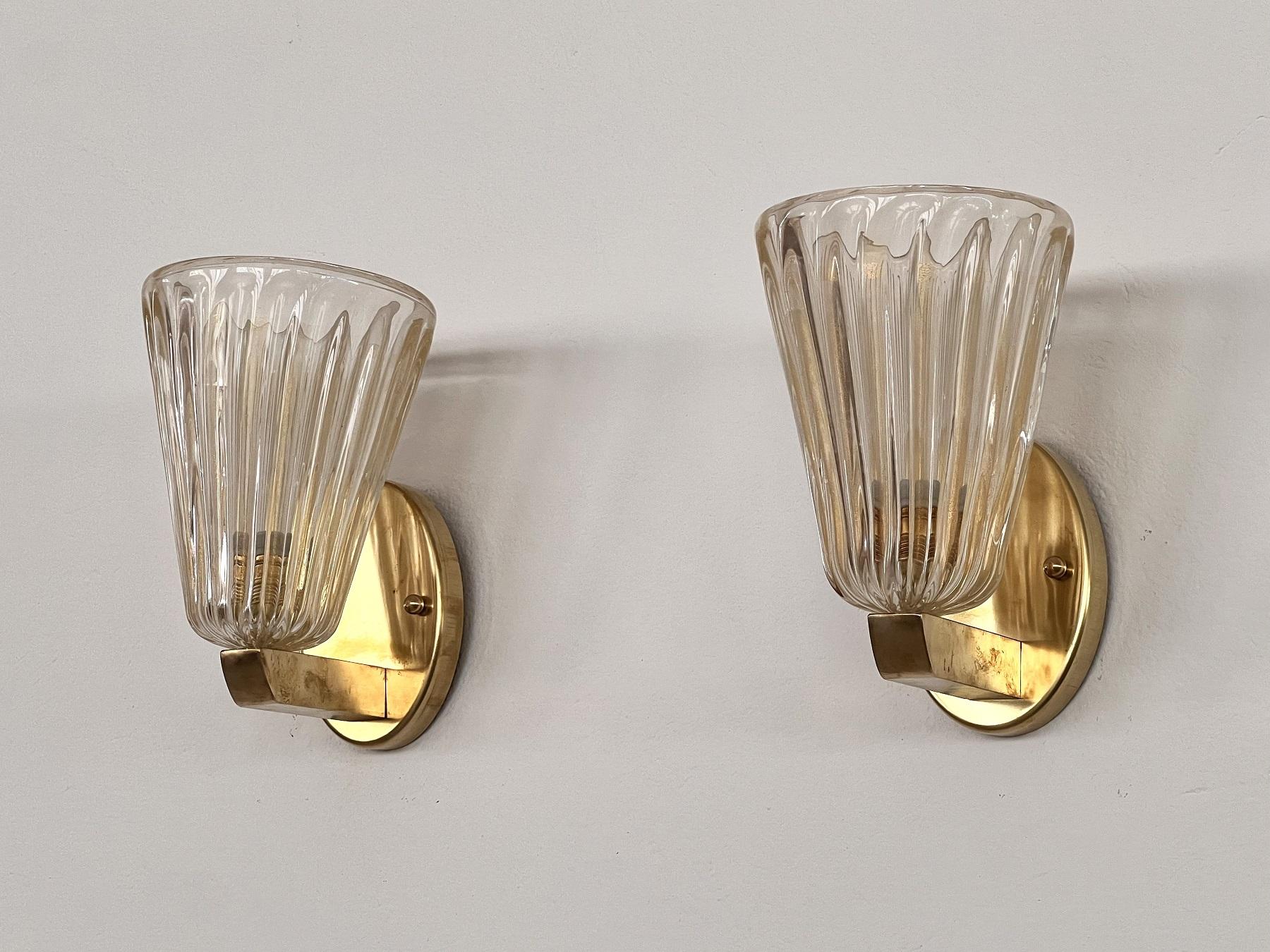 Beautiful set of two gorgeous brass wall lamps made of strong brass base and transparent Murano glasses with golden shimmer/glitter inside the glass. Art Deco style.
The beautiful hand-crafted glasses have a slight wave shape, please look carefully