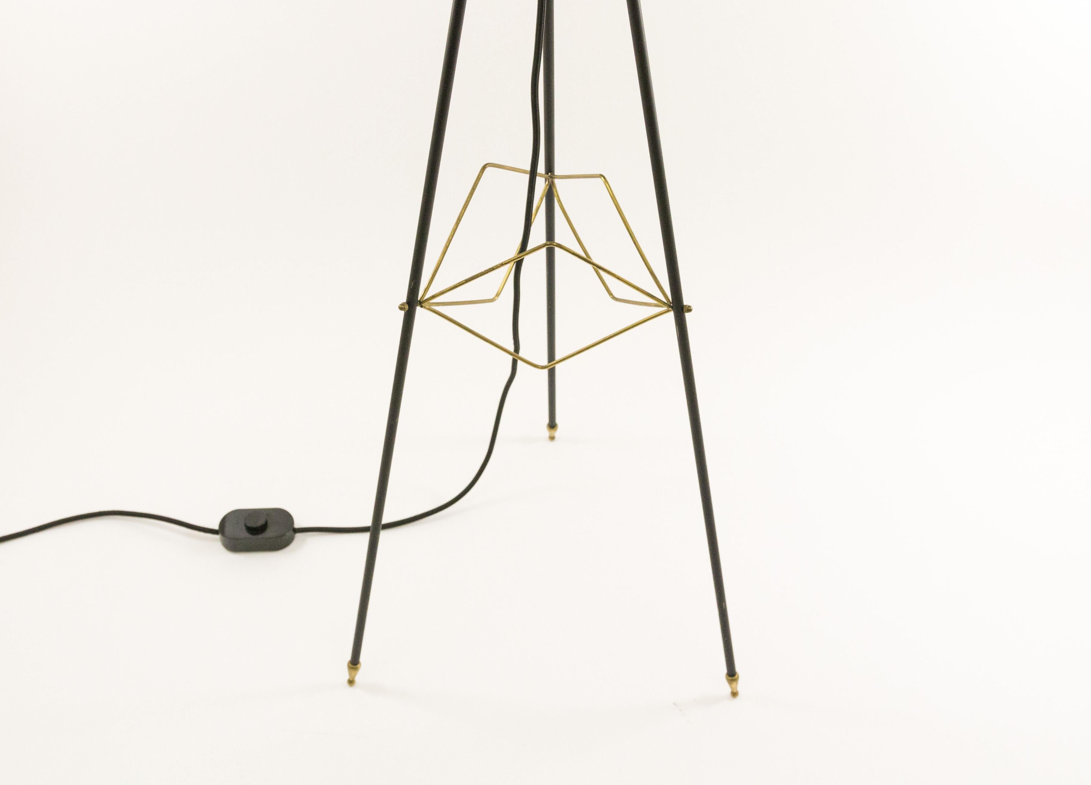 Tripod floor lamp designed and manufactured in Italy, 1950s. The lamp is made of black lacquered metal and white opaline glass. It features various elegant brass elements. The diameter of the opaline glass 'ufo shaped' shade is 40 cm.

The lamp is