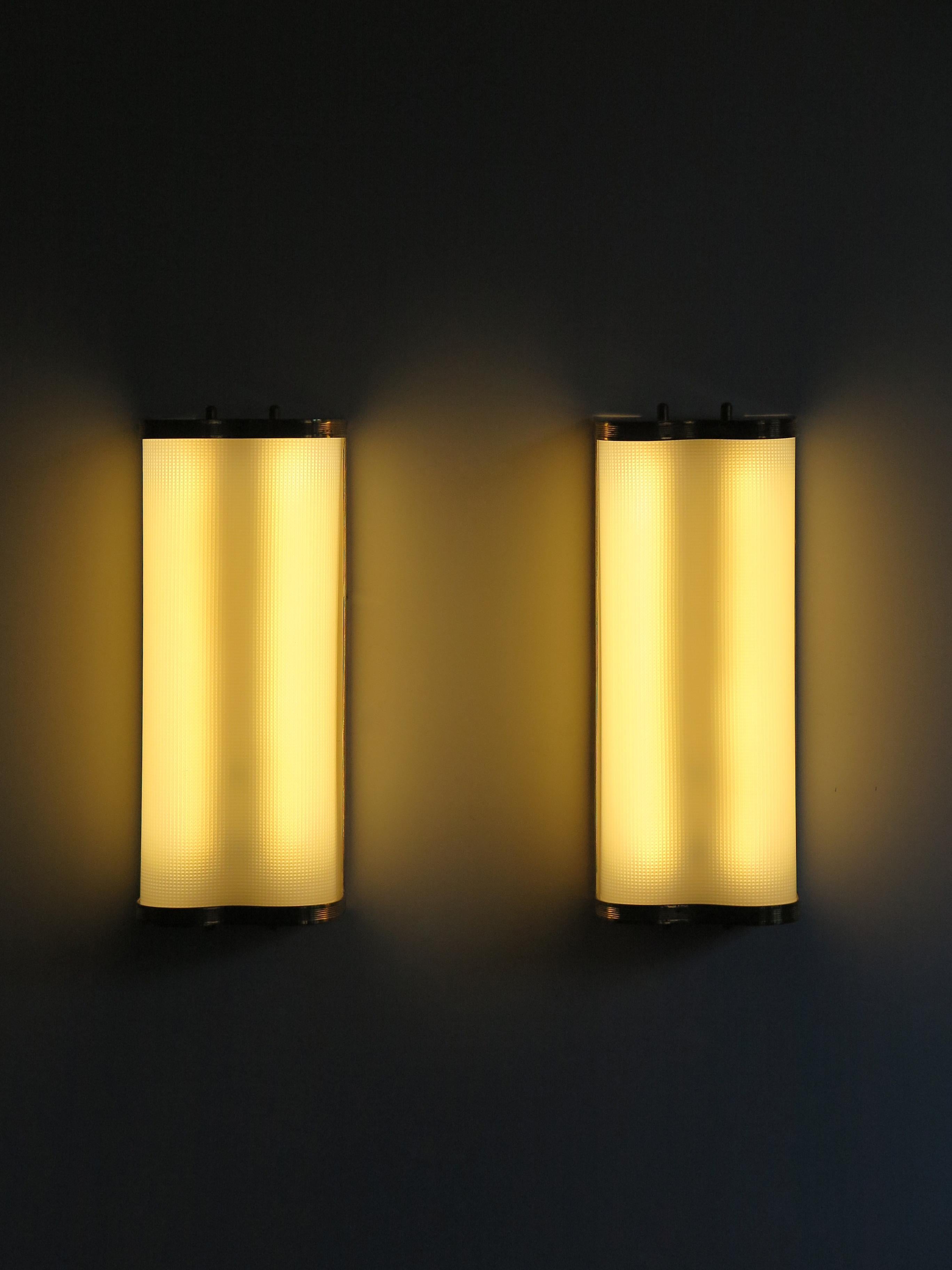 Midcentury modern design sconces wall lamps with brass structure and curved plexiglass diffuser, 1950s Italian production.
New electrical system with LED lights. 

Please note that the lamps are original of the period and this shows normal signs