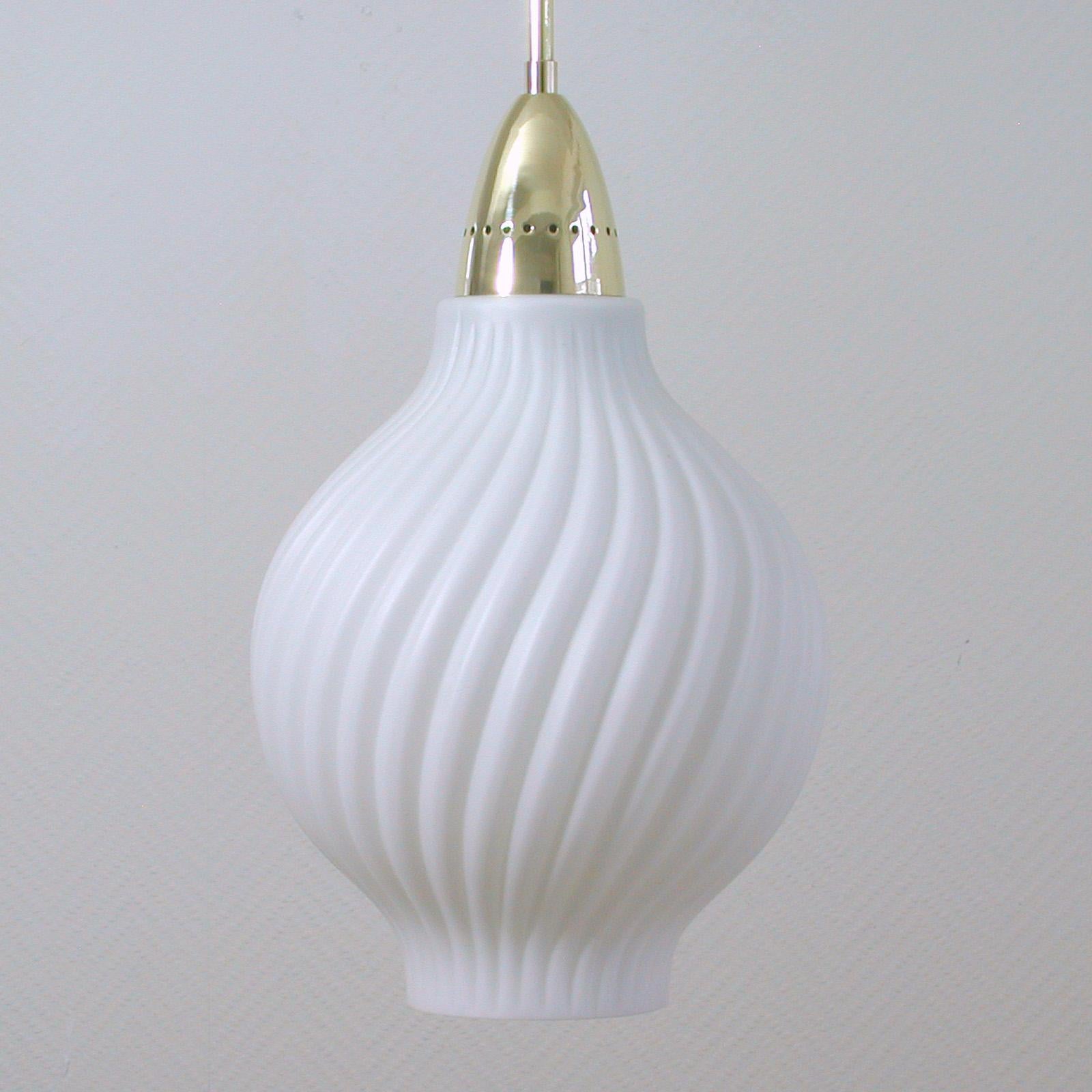 Diese elegante italienische Pendelleuchte wurde in den 1950er Jahren in Italien entworfen und hergestellt.

Sie hat einen schönen weißen Lampenschirm aus geripptem Glas mit Messingaufsatz, einen Lampenstab aus Messing und einen Baldachin aus