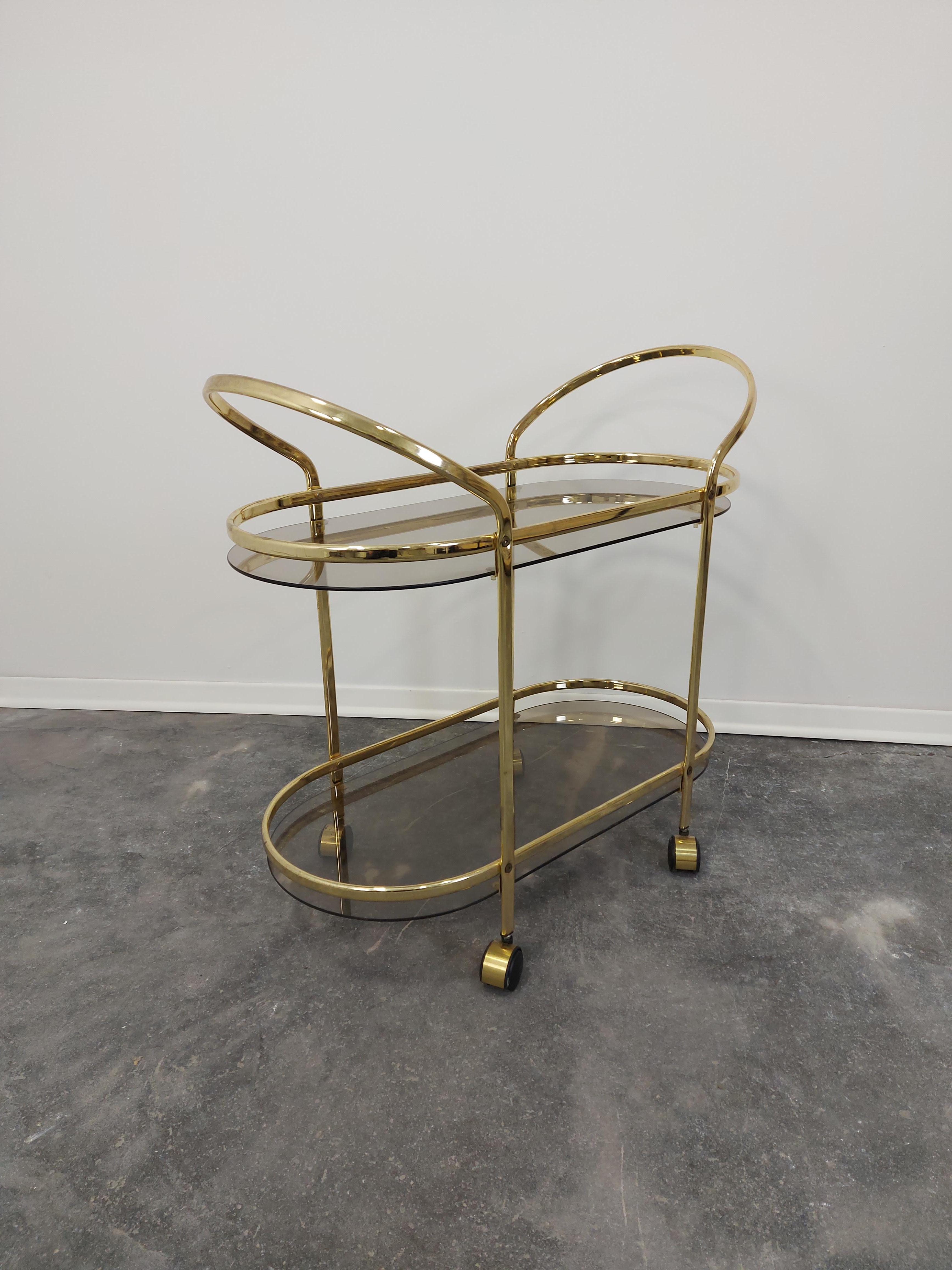 Italian brass and smoked glass bar cart 1960s

Perfect in that upscale home with chic design. 

Two tiered for storage. 

Wheel from room to room for your convenience.

Measures: H-78 cm (1 tier-13 cm, 2 tier-50 cm) , W-82 cm, D-39 cm.