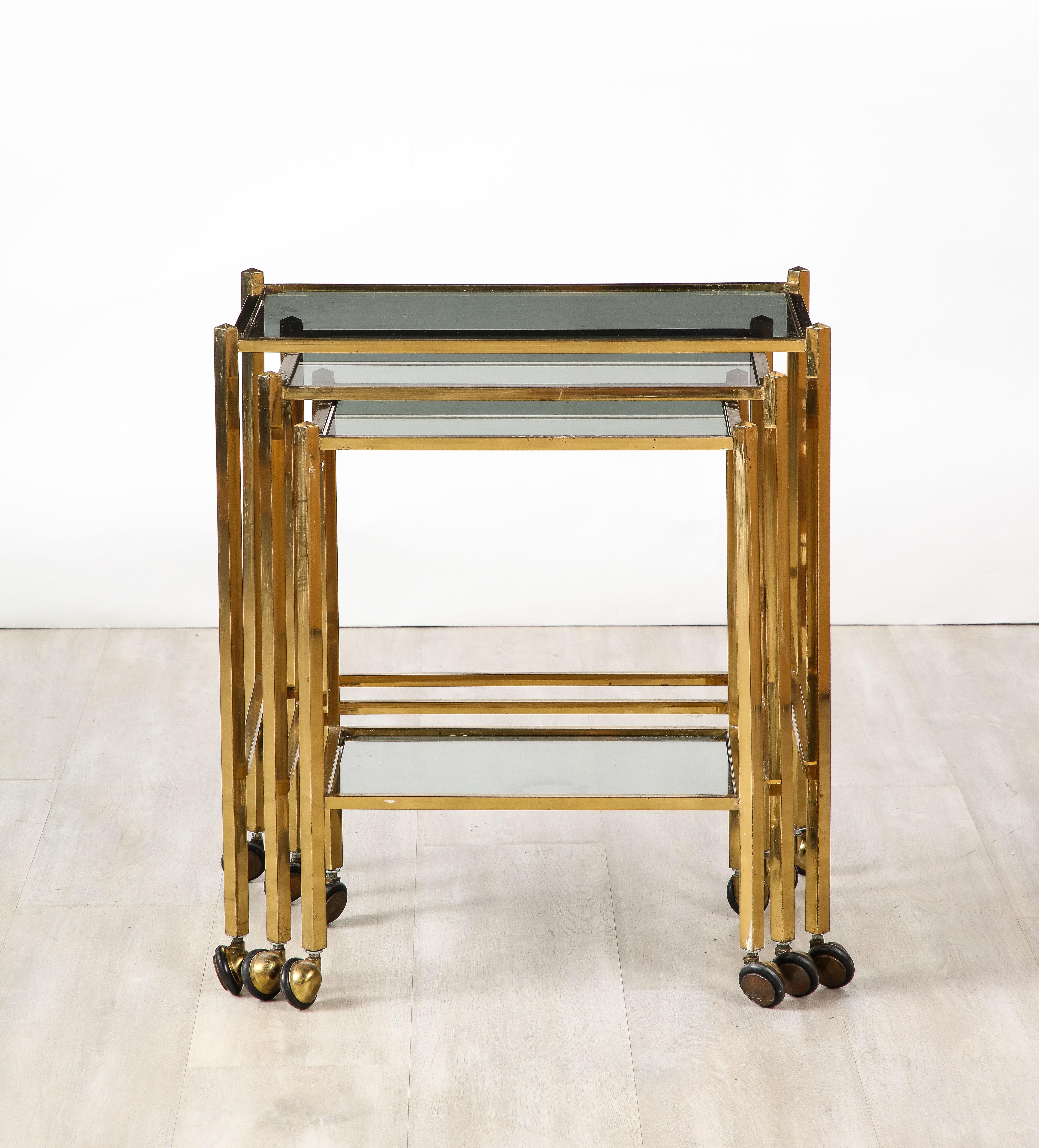 Set of three Italian mid-century modern brass and smoked glass nesting tables with rolling feet. Highly practical, classic and chic, perfect for any interior style.
Italy, circa 1960 
Size: Tallest table: 23 1/4