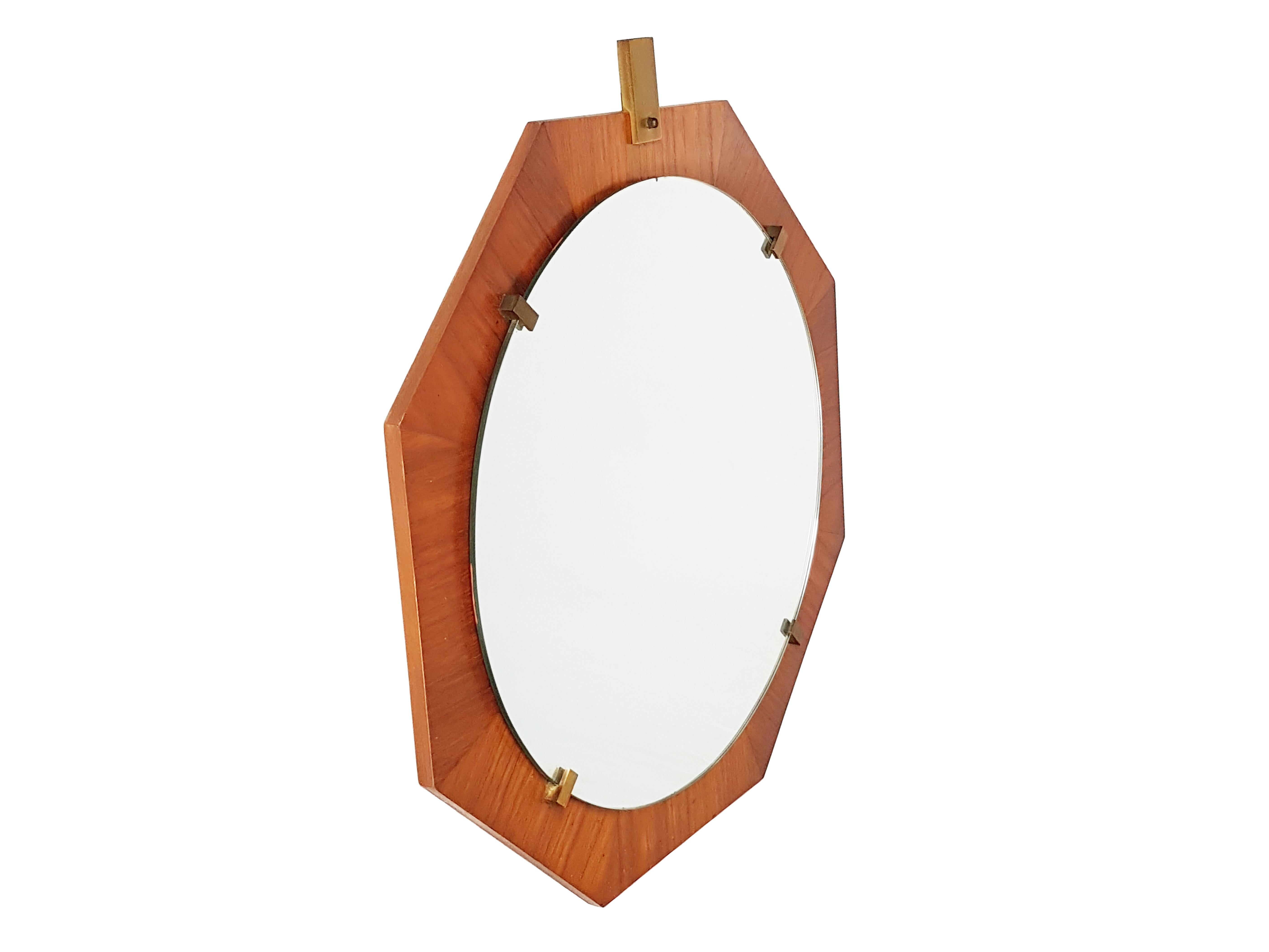 This mirror was produced in Italy in the 1960s. It has an octagonal shape and it is made from a teak structure with brass holders and a round mirrored glass. It remains in very good vintage condition.