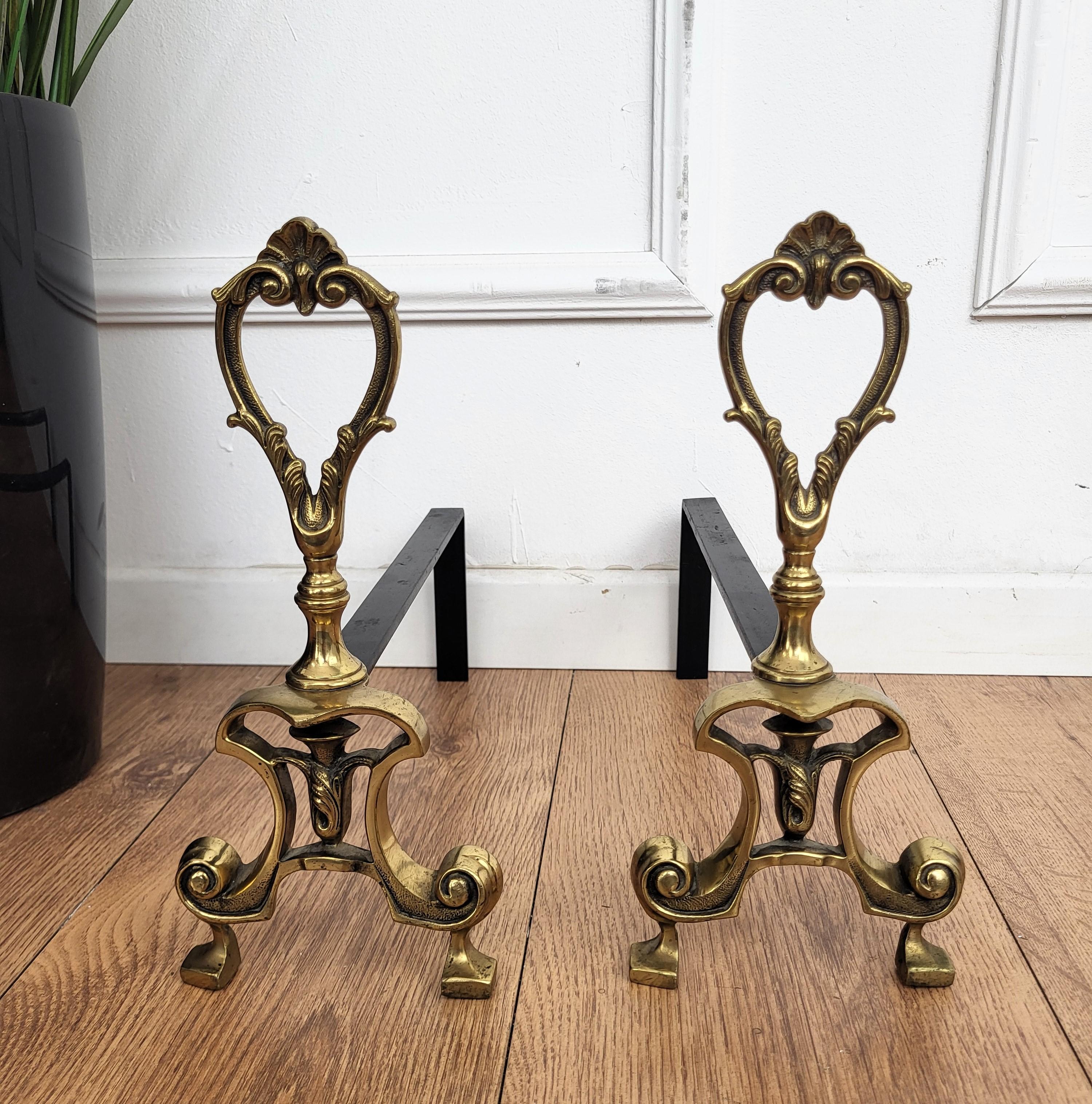 Pair of Italian brass andirons, having the usual back in wrought-iron pillars with the beautiful front classic themed brass decor detail. As can be seen in the pictures we do have as well available in the same decor the other fire place pieces tool