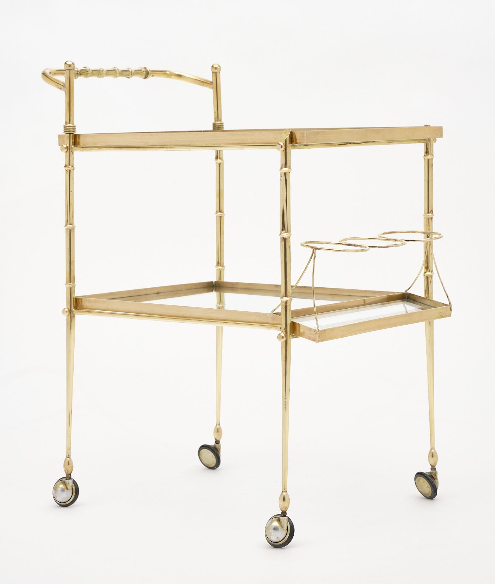 Bar cart from the Art Deco period in Italy made of polished brass. This piece features a bottle holder and two clear glass shelves. It is all original.