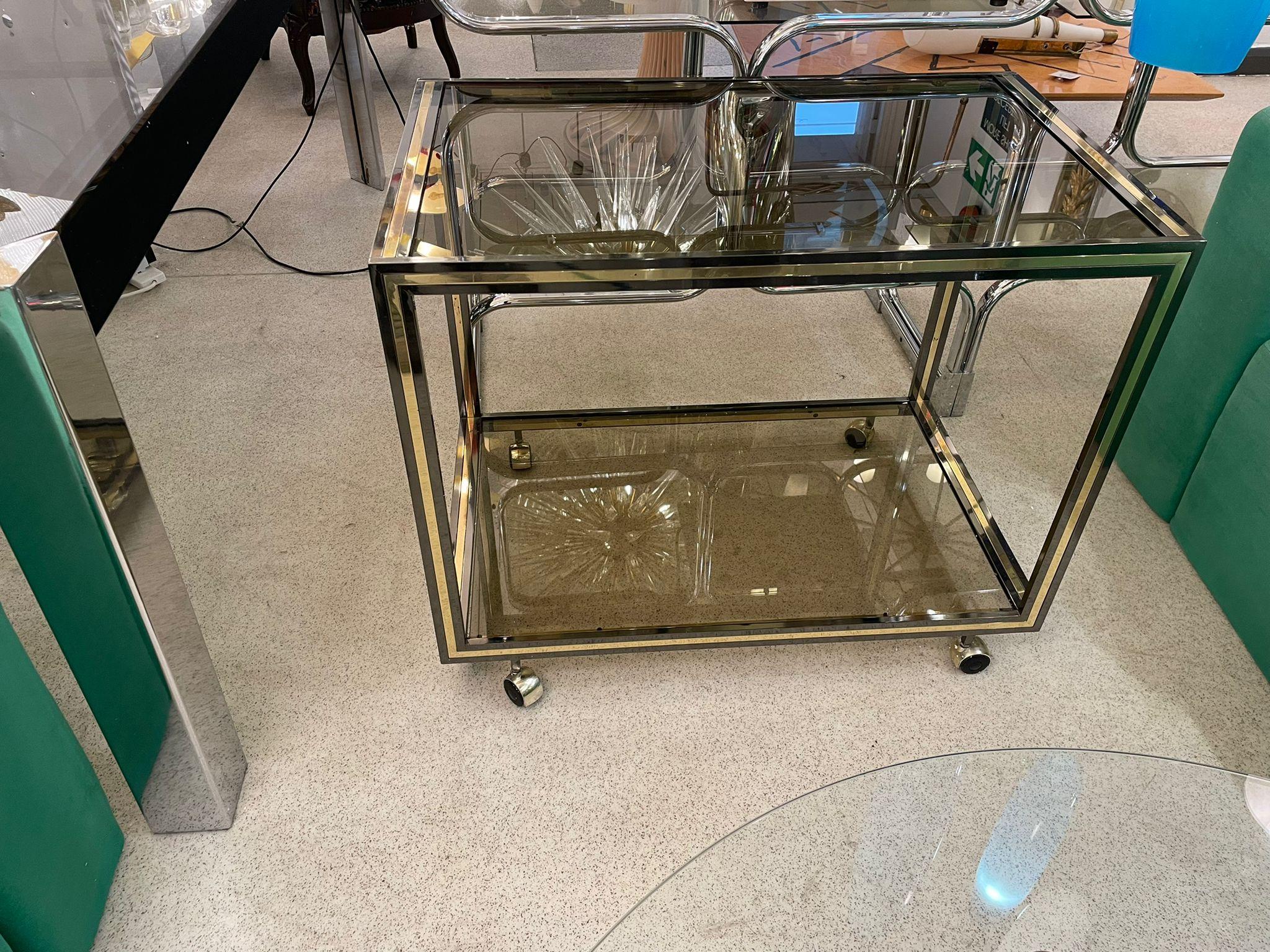 Mid-century bar cart, circa 1960, Italy. Brass and two smoked glass shelves.
 