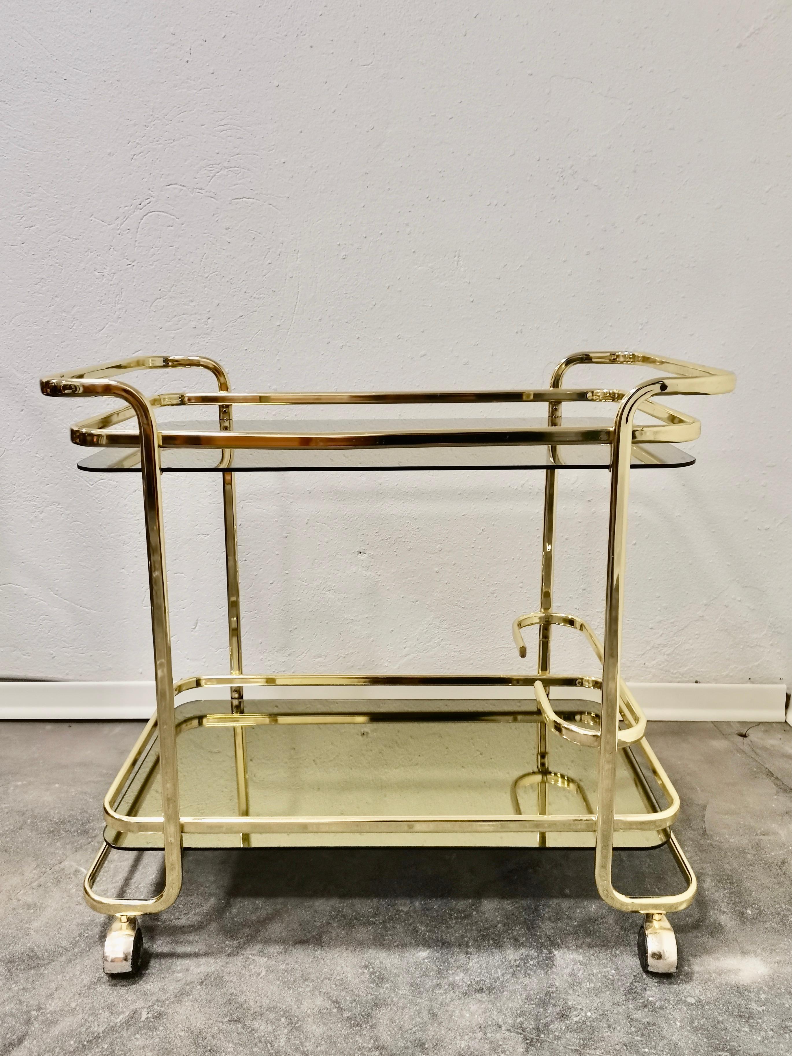 Magnificent Italian brass vintage bar cart. All original parts.The trolley has two shelves, the lower shelf is in golden mirror and the upper shelf is in smoked glass

Period: 1980s

Country of producer: Italy

Style: Hollywood regency Style,