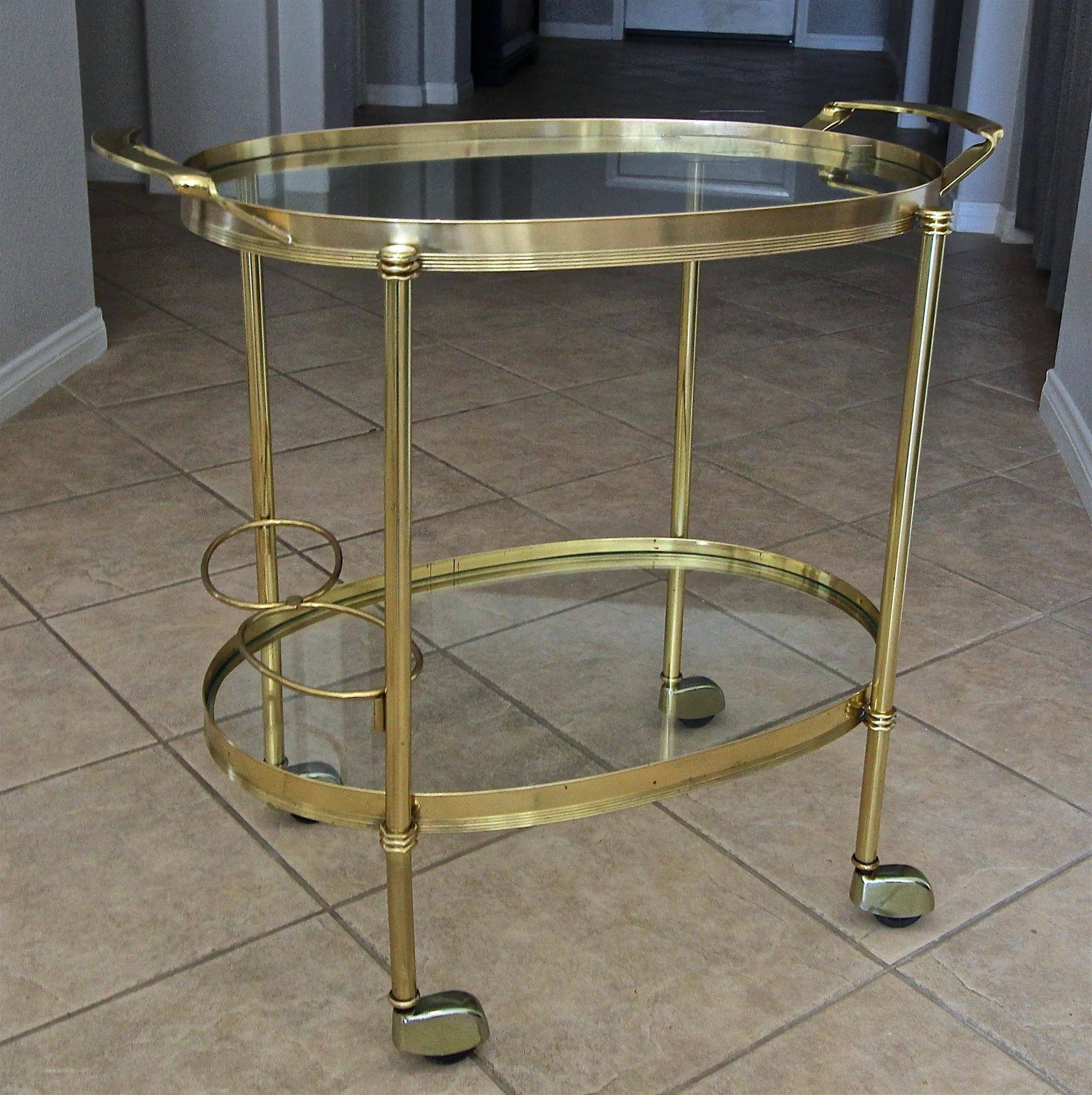 Italian 2-tier solid brass bar (or tea cart) with bottle holder and inset glass shelves. Has nice clean lines, would be a great addition to any traditional or modern setting.
Dimensions: Height to top of handle is 26