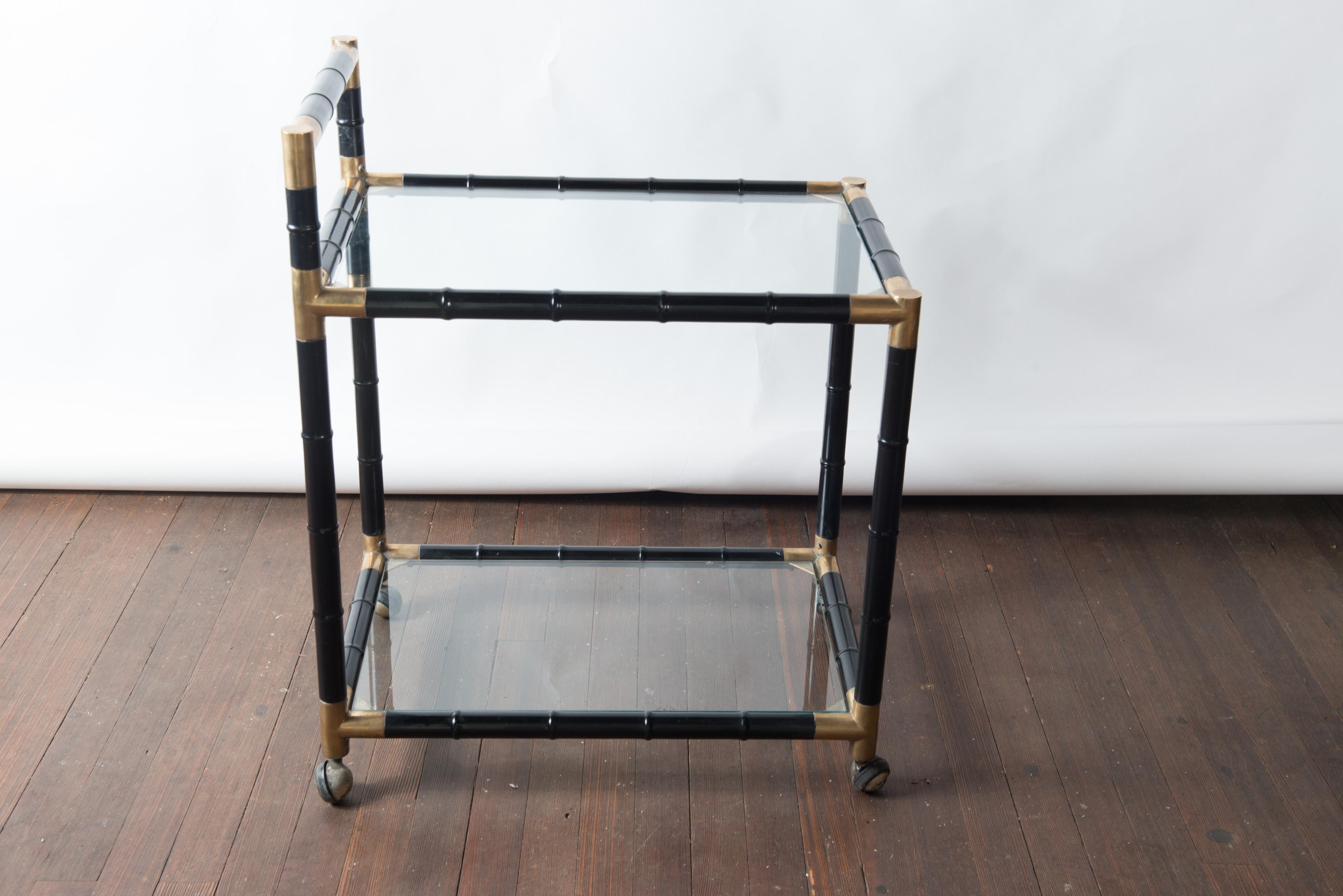 Black painted, brass trimmed, wood faux bamboo bar or drinks cart on ball casters.
In the style of Billy Haines or Tony Duquette. Glass surfaces. Clean lines.