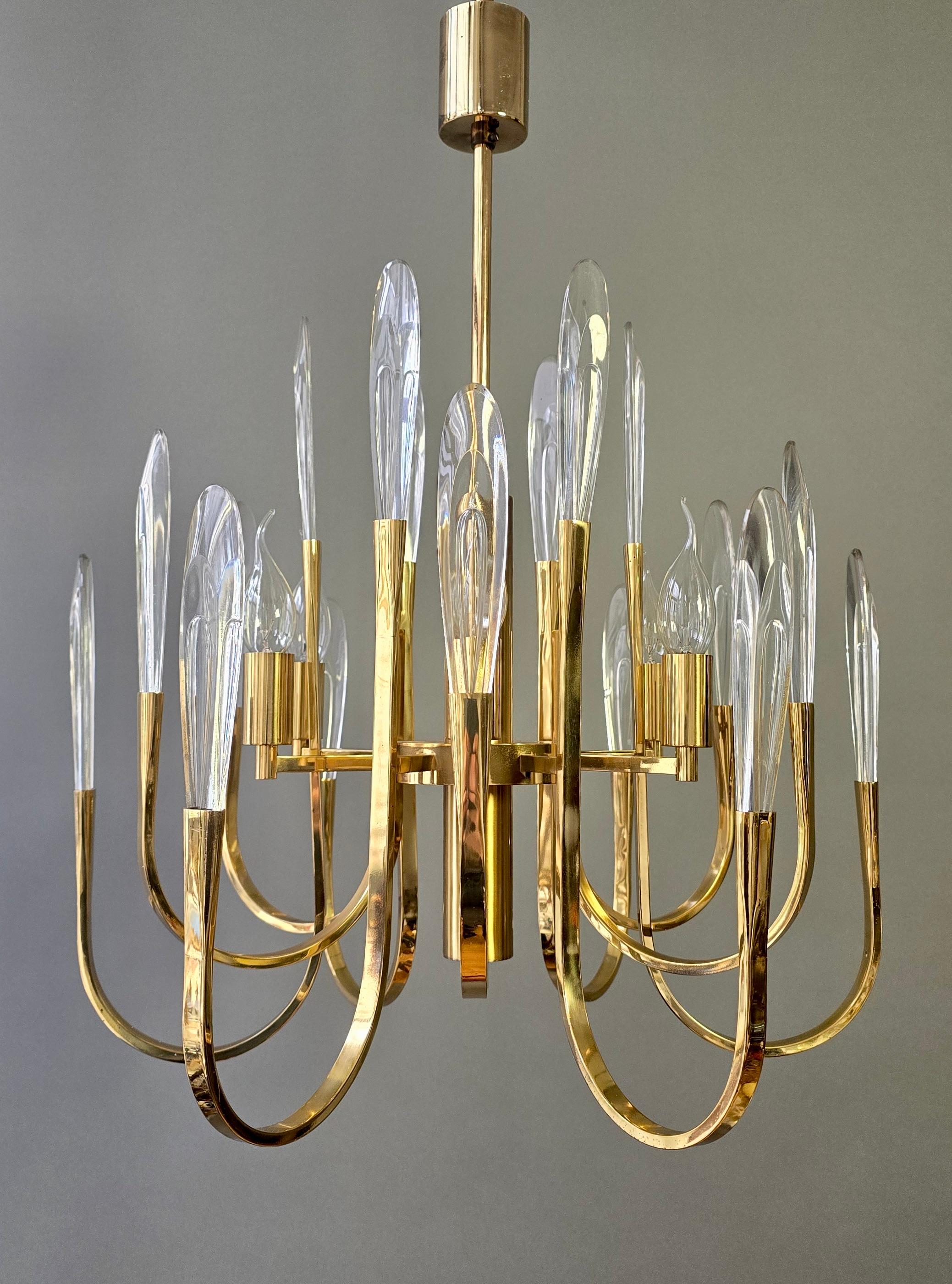 Lustre italien en laiton à six lumières avec de hautes flammes en verre massif, années 1970. Un design raffiné dans le style Scolari avec un verre sculptural clair et des bras courbés en laiton.

Lustre italien des années 1970, conçu dans le style