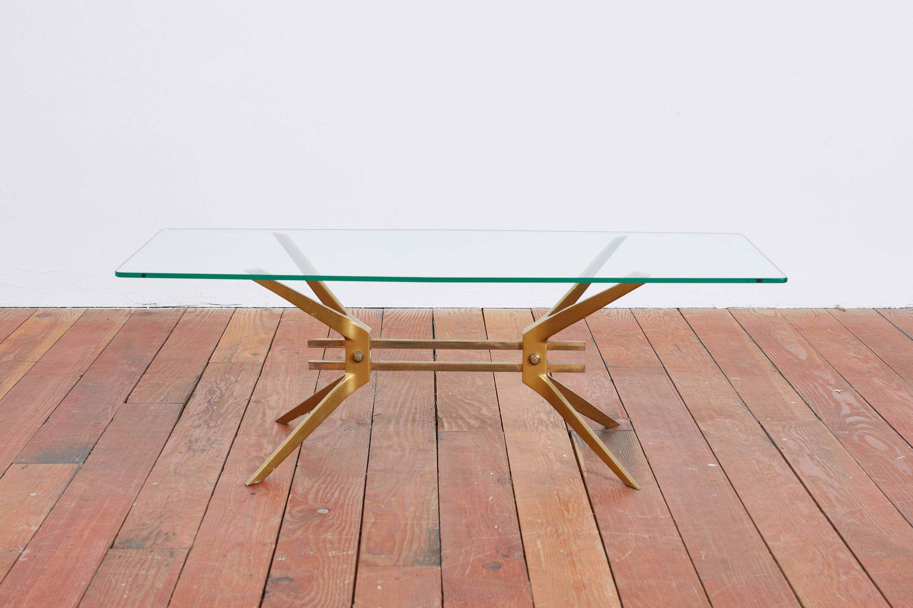 1960's Italian brass and glass coffee table 
Thick heavy brass base with angular legs 
Glass top slightly bows out in the middle of rectangular shaped top 
Simple elegant piece 
Italy, 1960s
