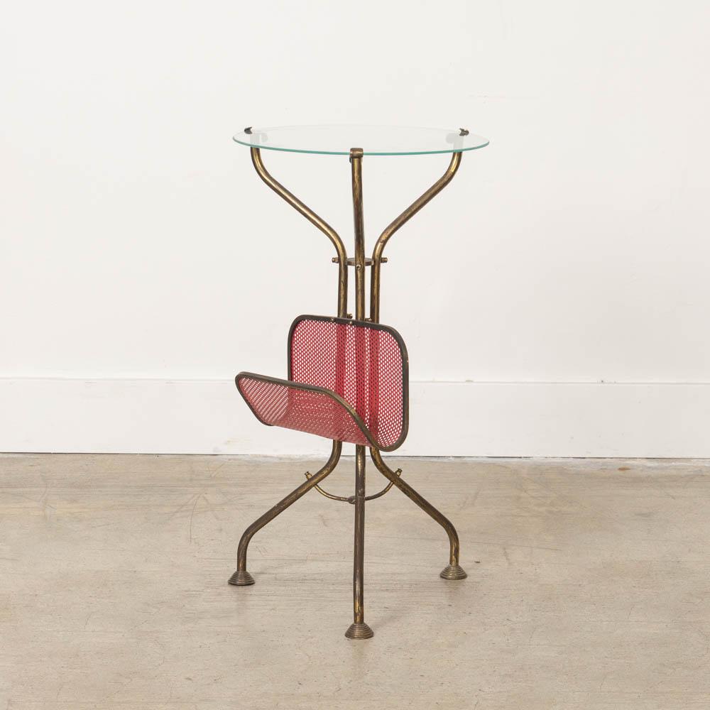 Beautiful Italian brass circular table with glass top from the 1950s. Original brass base with three curved legs and perforated red metal magazine rack. Newly replaced glass top. Perfect as a side table. Original brass finish shows nice age and