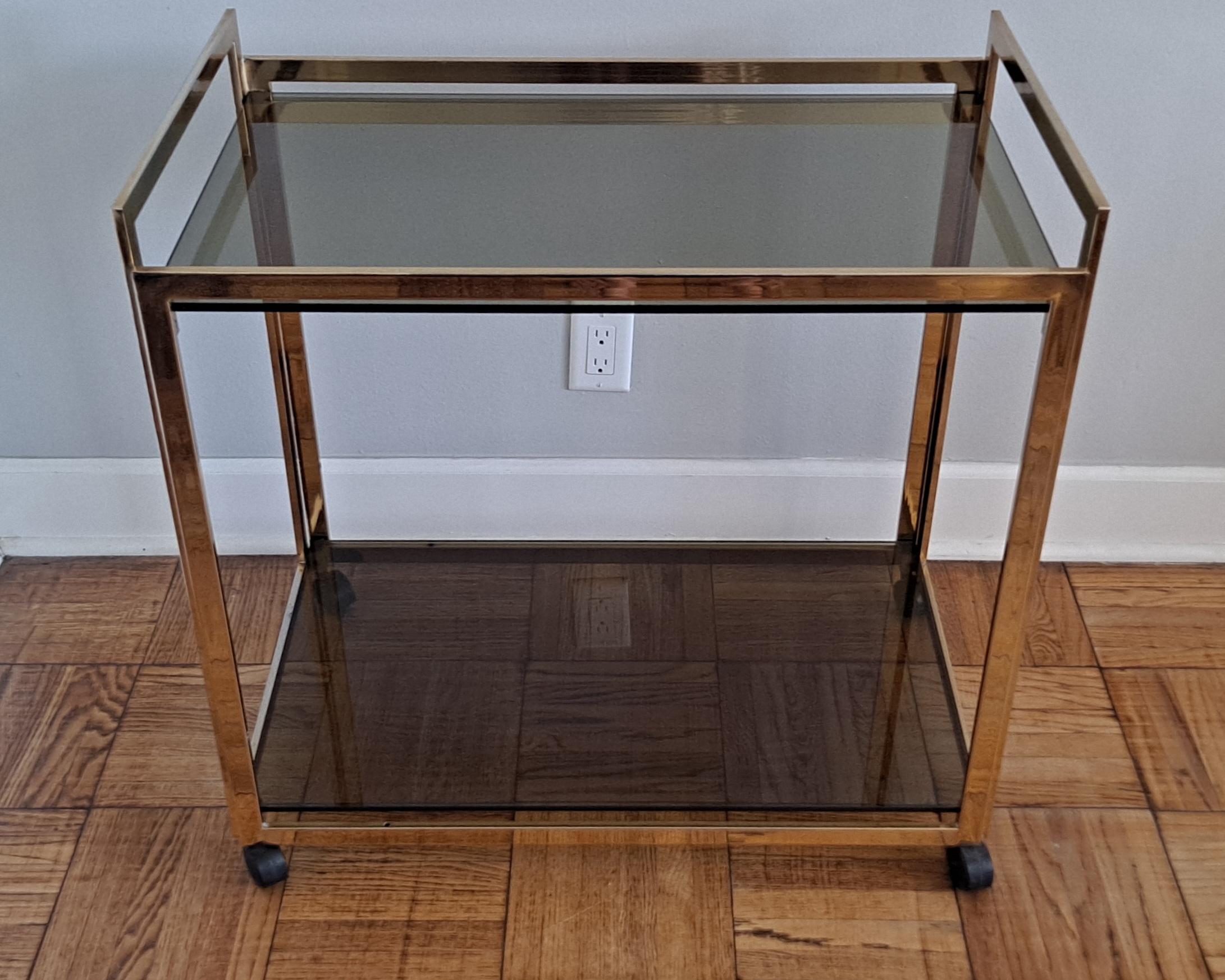 This stylish service cart has fume 1 cm tick fume glass top. It is on the wheals and it is easy to move .Base is brass and it is very good structurally but the brass is tarnish, bar cart it is  made with a lot of taste . 
USA continental  in home