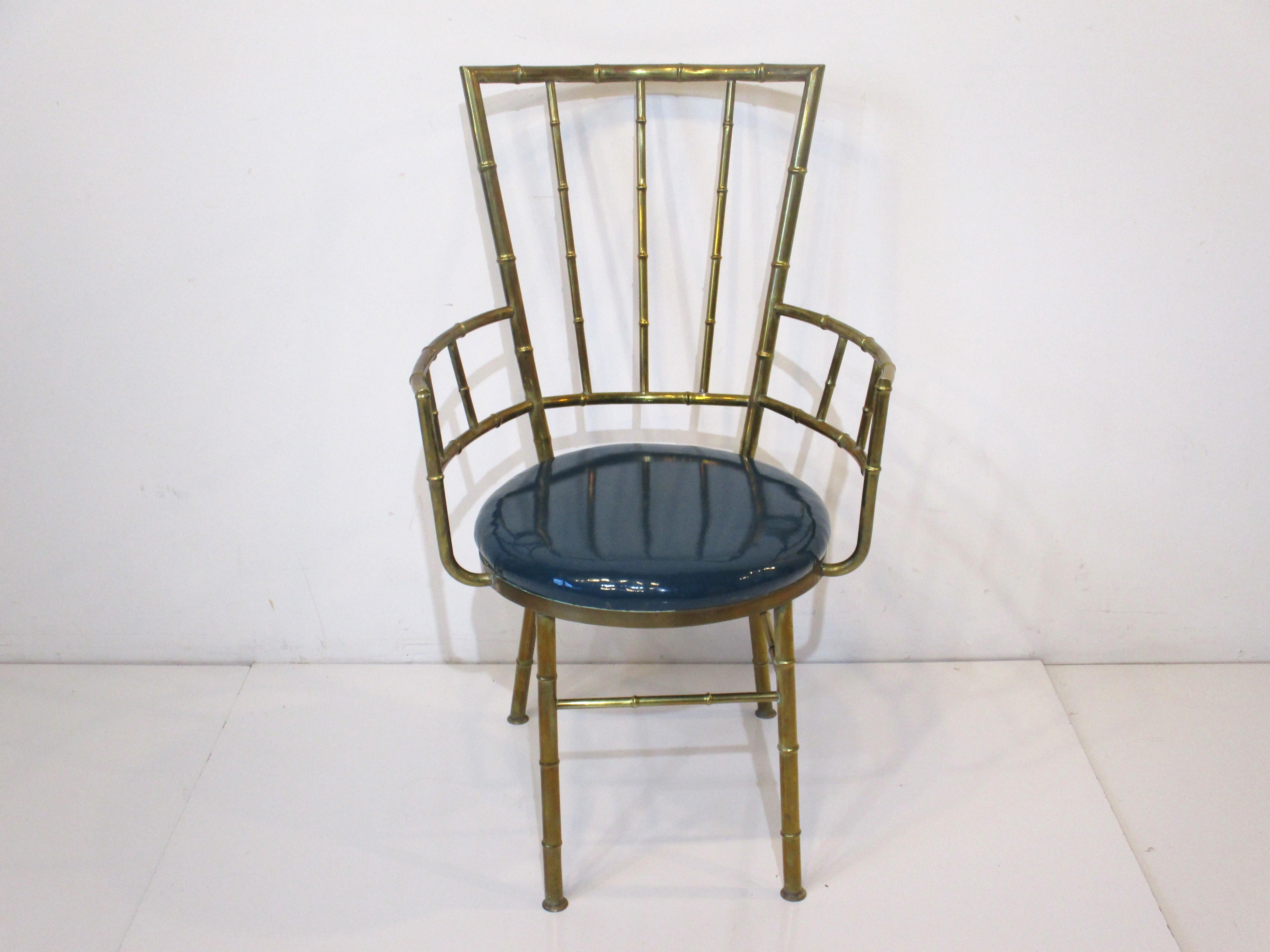 A very elegant faux bamboo styled brass arm chair with upholstered seat in a glossy high grade deep marine blue green vinyl fabric. This well crafted chair is in a small scale perfect for that added detailed piece for your living space or dressing