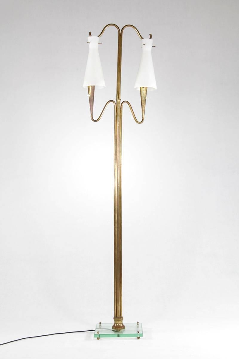 Lampada da terra italiana, anni '50. La lampada è realizzata in ottone e ha due paralumi in vetro opalino su una base in vetro cristallo.

 