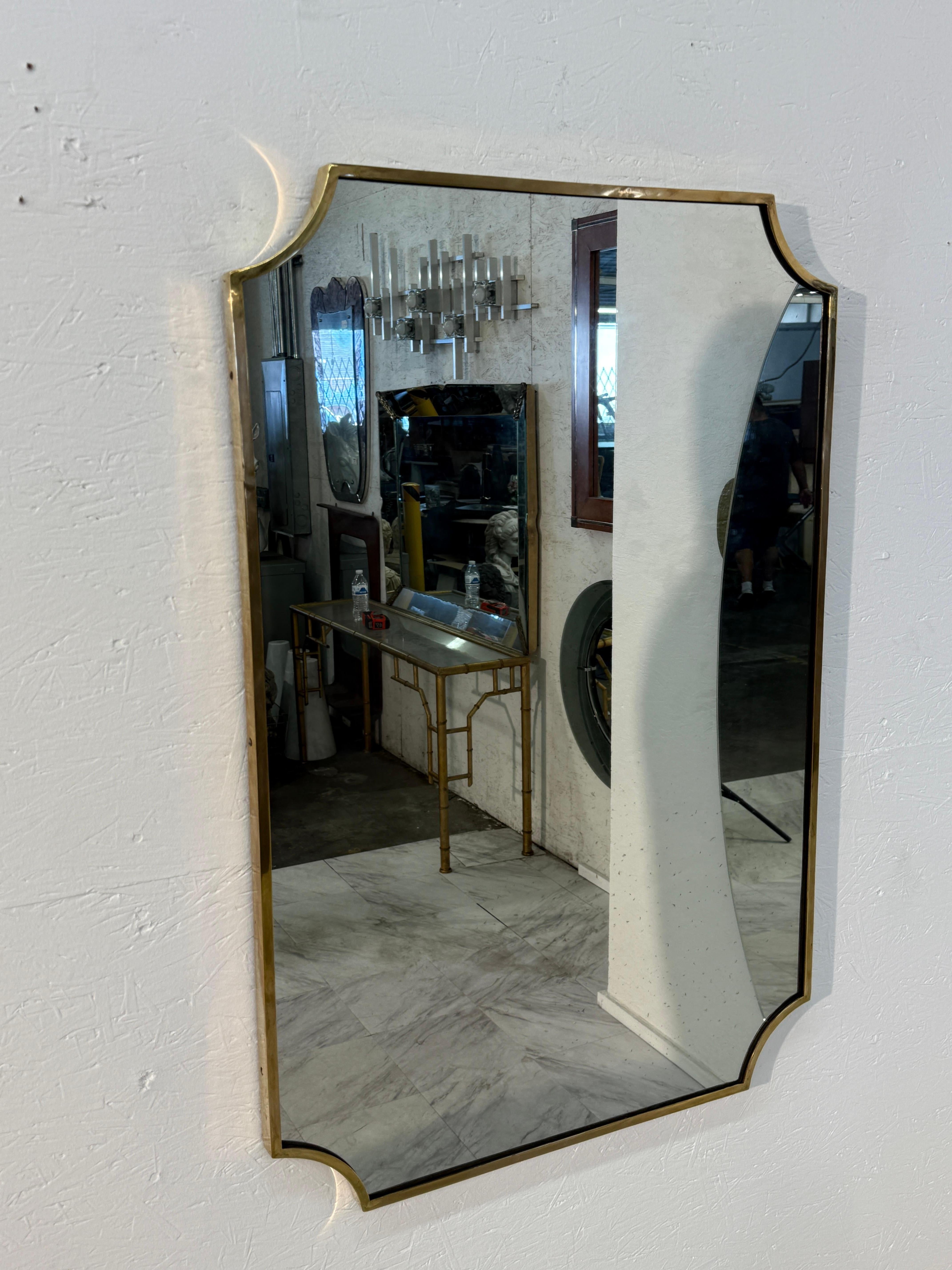 A tall, rectangular Italian wall mirror with elegant notched corners and a minimalist design. The frame is made of solid brass with a polished surface that has developed a warm vintage patina over time. The clean lines and subtle curves at each