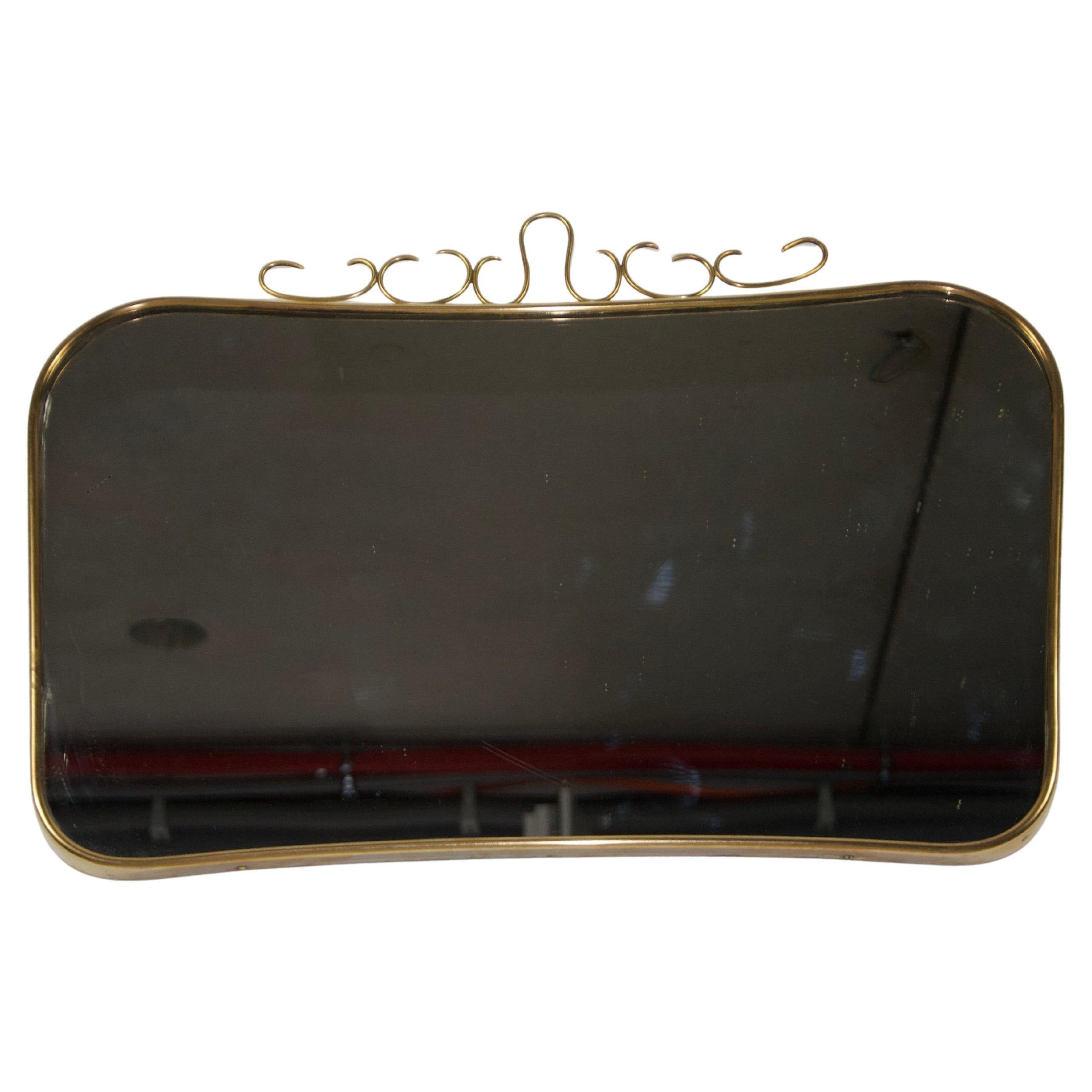 Miroir mural italien vintage des années 1960, entièrement réalisé en laiton et attribué à Gio Ponti. Le miroir est entouré d'un élégant cadre en laiton présentant des détails complexes. Ce design extraordinaire crée une apparence unique et