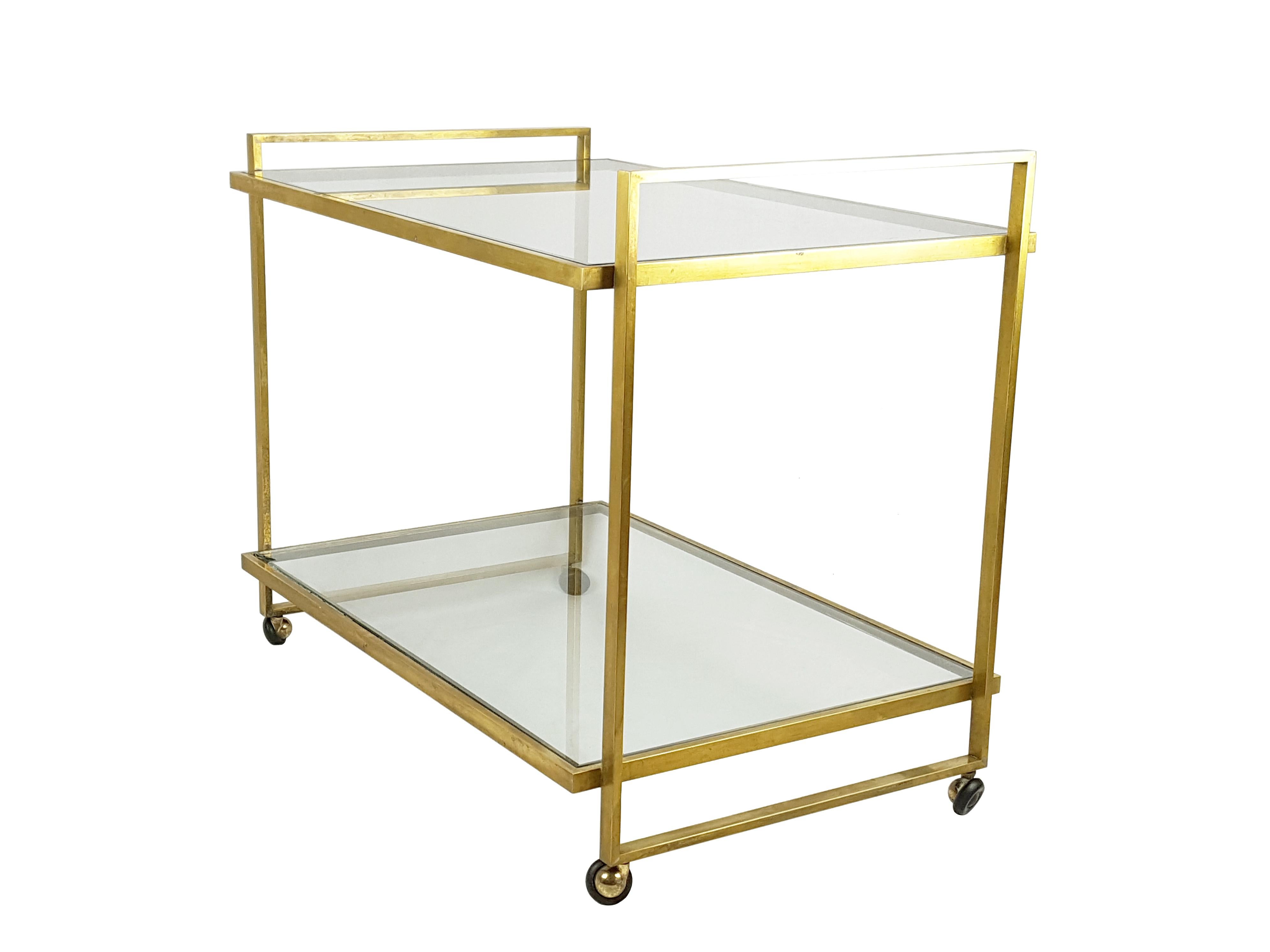 This vintage serving cart was manufactured in Italy in the 1970s. Its design is very minimal: the structure is made up by 4 brass frames welded together and by 2 glass shelves. It remains in a very good condition: patina on the brass frames due to