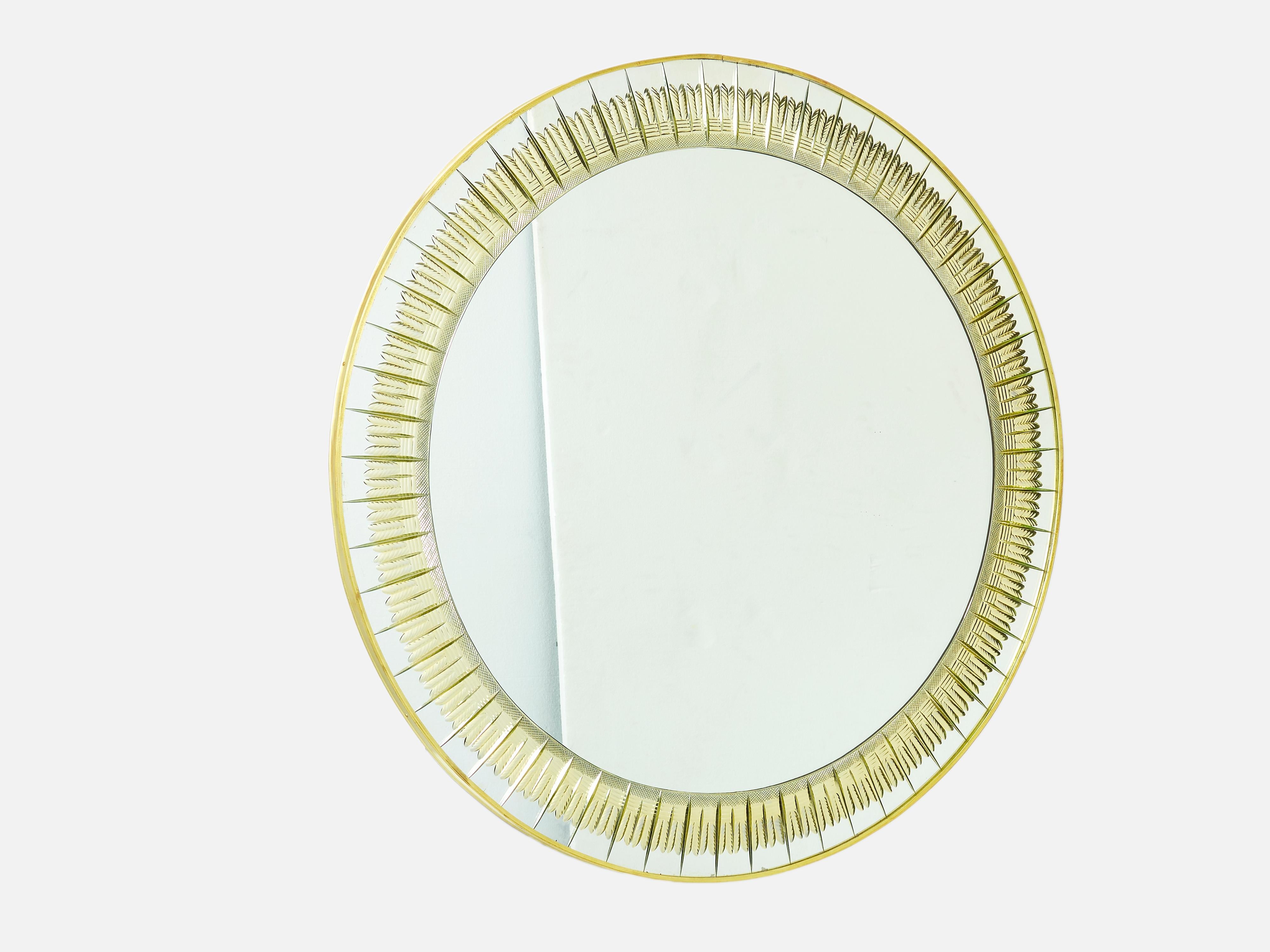 With its strong design, this round brass mirror was made by Cristal Arte in the early 1960s. This wall mirror features a golden colored engraved crystal edging with brass frame border and trim. A perfect mirror for an entrance, a living room or