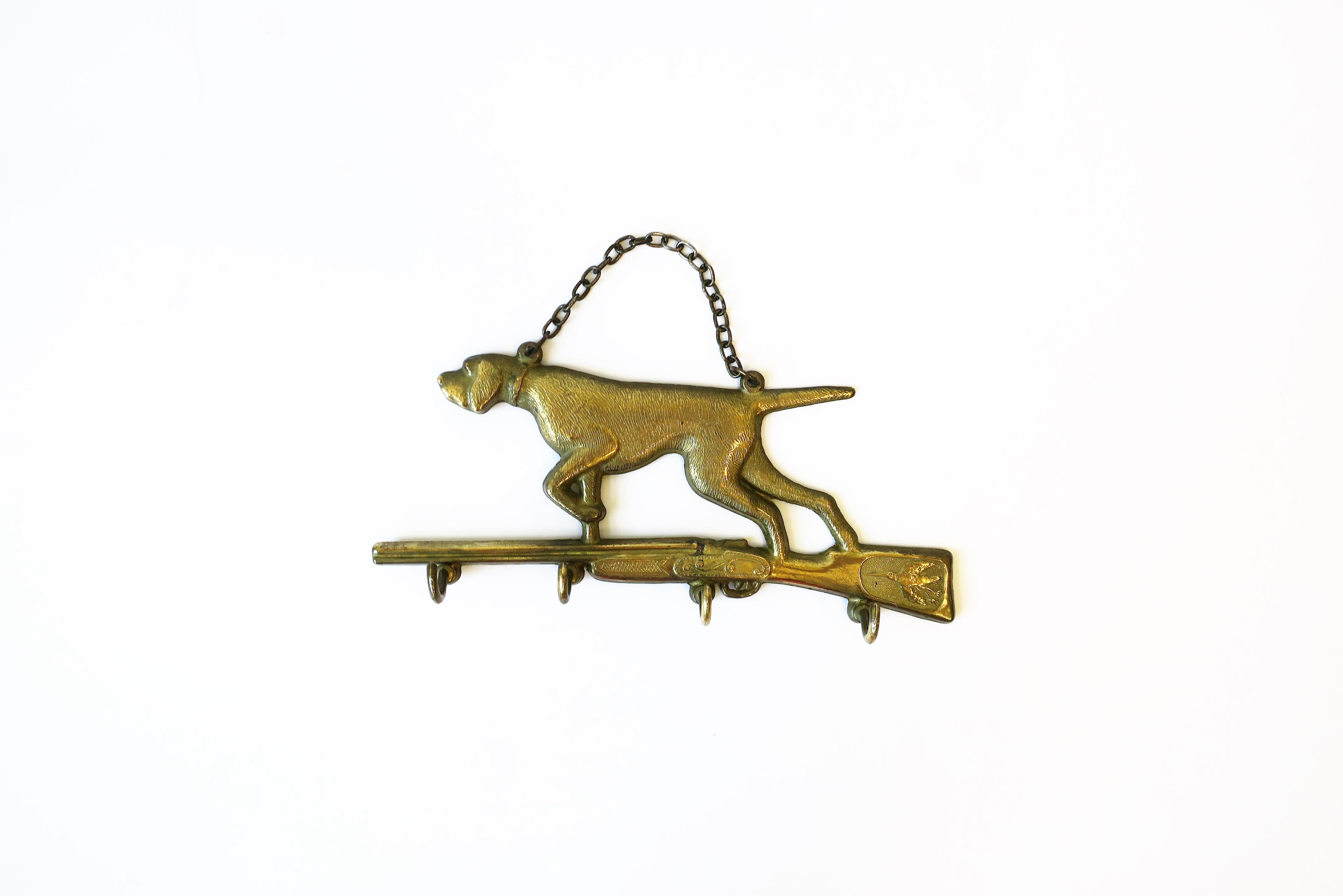 A great Italian brass hunting dog and rifle wall key hook holder, circa early to mid-20th century, Italy. Piece features a bloodhound hunting dog atop a rifle gun. Gun with pheasant bird detail. Below gun there are four (4) hooks for keys or other
