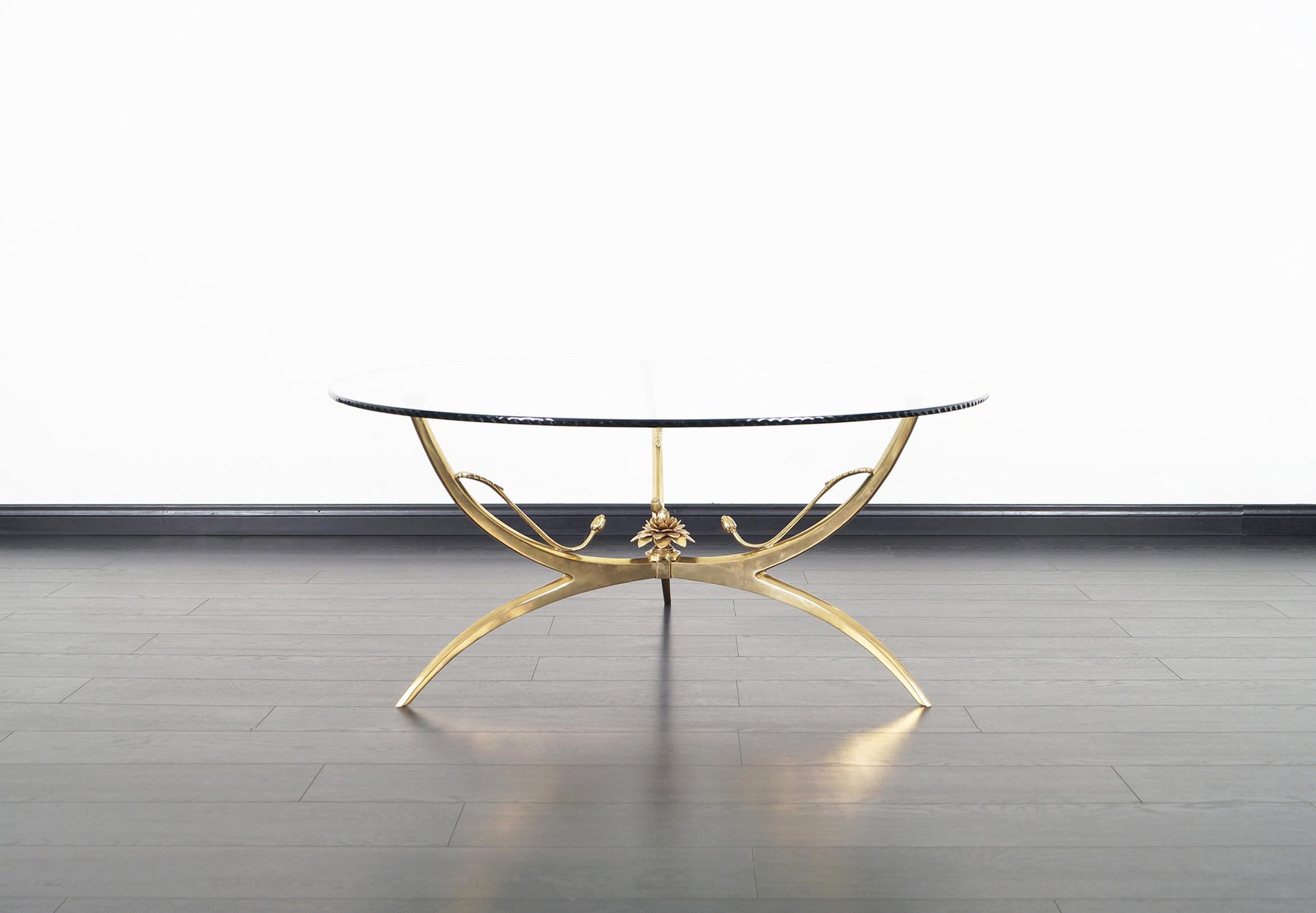 Elegant vintage brass coffee table designed in Italy, circa 1970s. This beautiful table features a solid brass base with a lotus flower in the center, supporting the original glass top which features an artistic wave-edge finish.