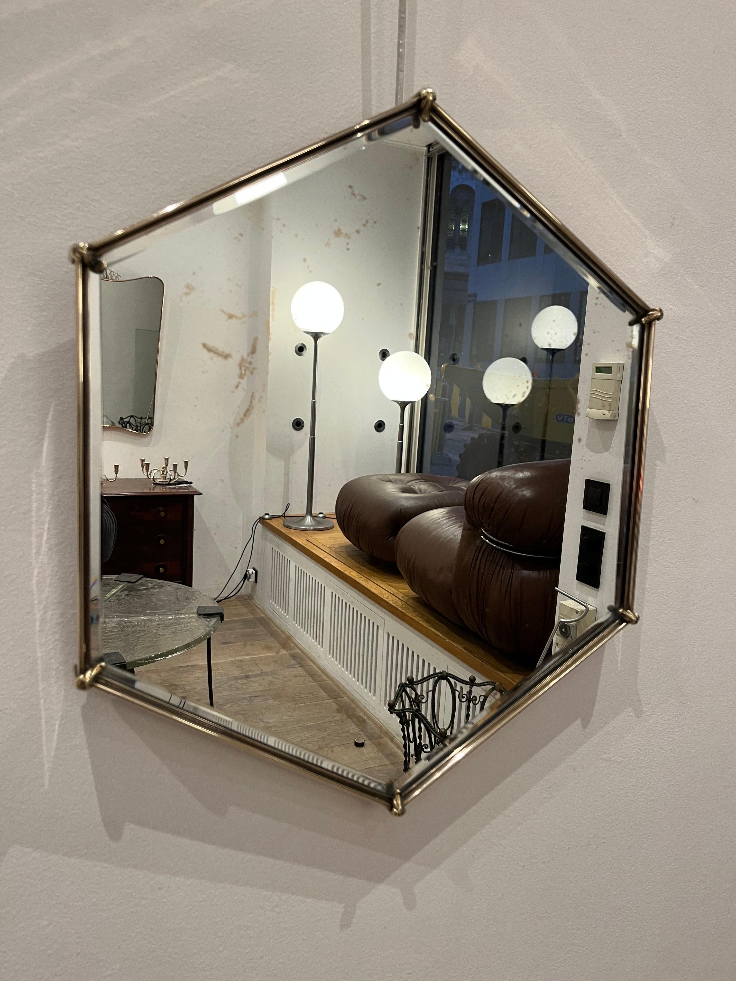 Italian mirror in a polygonal shape. Made of brass with applied brass chiselled leaves on the corner (see photos). Mirrors like this one were created in the 1940s in Italy. They are highly decorative.