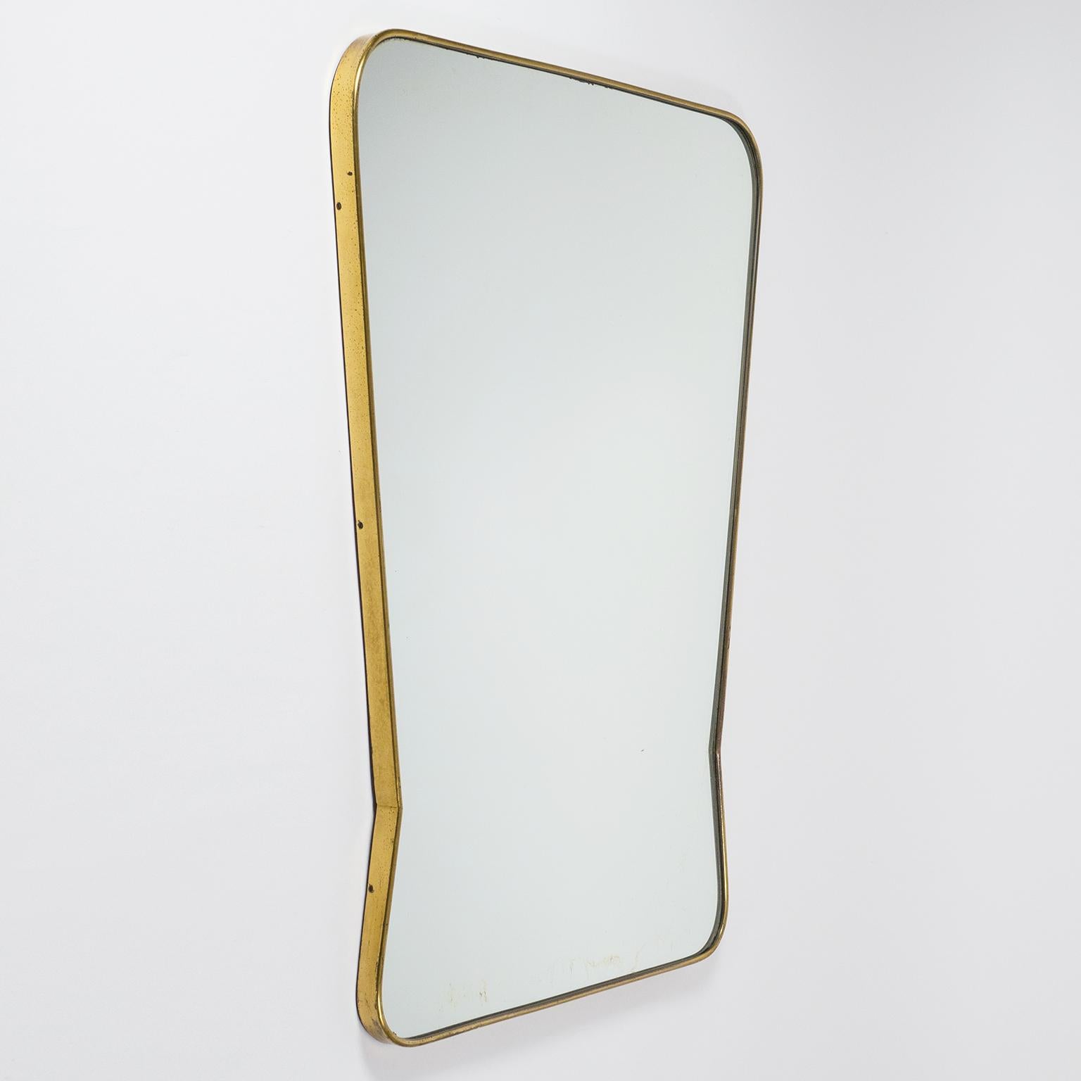 Very fine 1940s-1950s Italian brass mirror, attributed to Fonatan Arte. The continuous brass frame has a very unique tapered shape reminiscent of Gio Ponti designs. Good original condition with patina on the brass and some wear to the silver coating