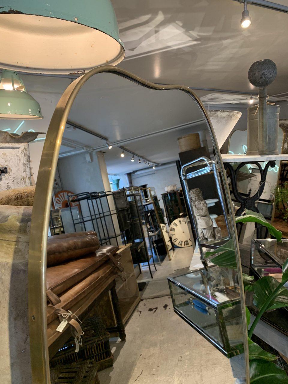 Sophisticated and sleek Italian brass mirror from the 1960s, with a beautiful curved design and a simple brass profile. The mirrored glass is original and it is stylistically related to the well-known designer Giò Ponti.

Particularly eye catching