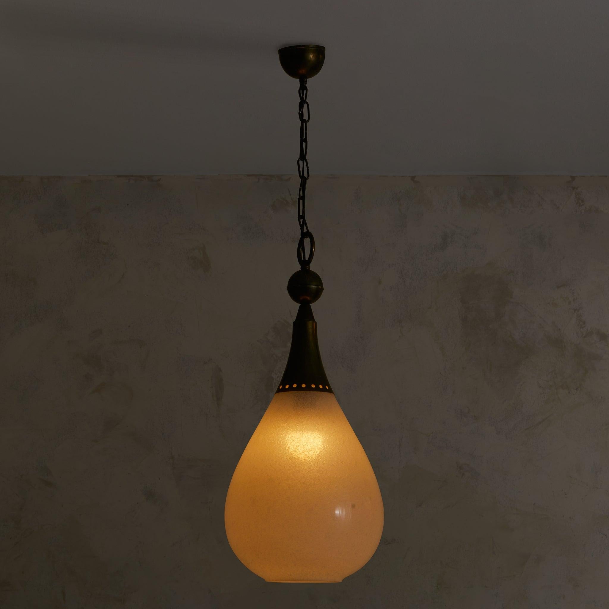 An expression of midcentury Italian design, this 1950s pendant light distills form to its most essential. Crafted from delicate opaline glass, the teardrop-shaped shade diffuses light with a soft, atmospheric glow. A patinated brass finial and