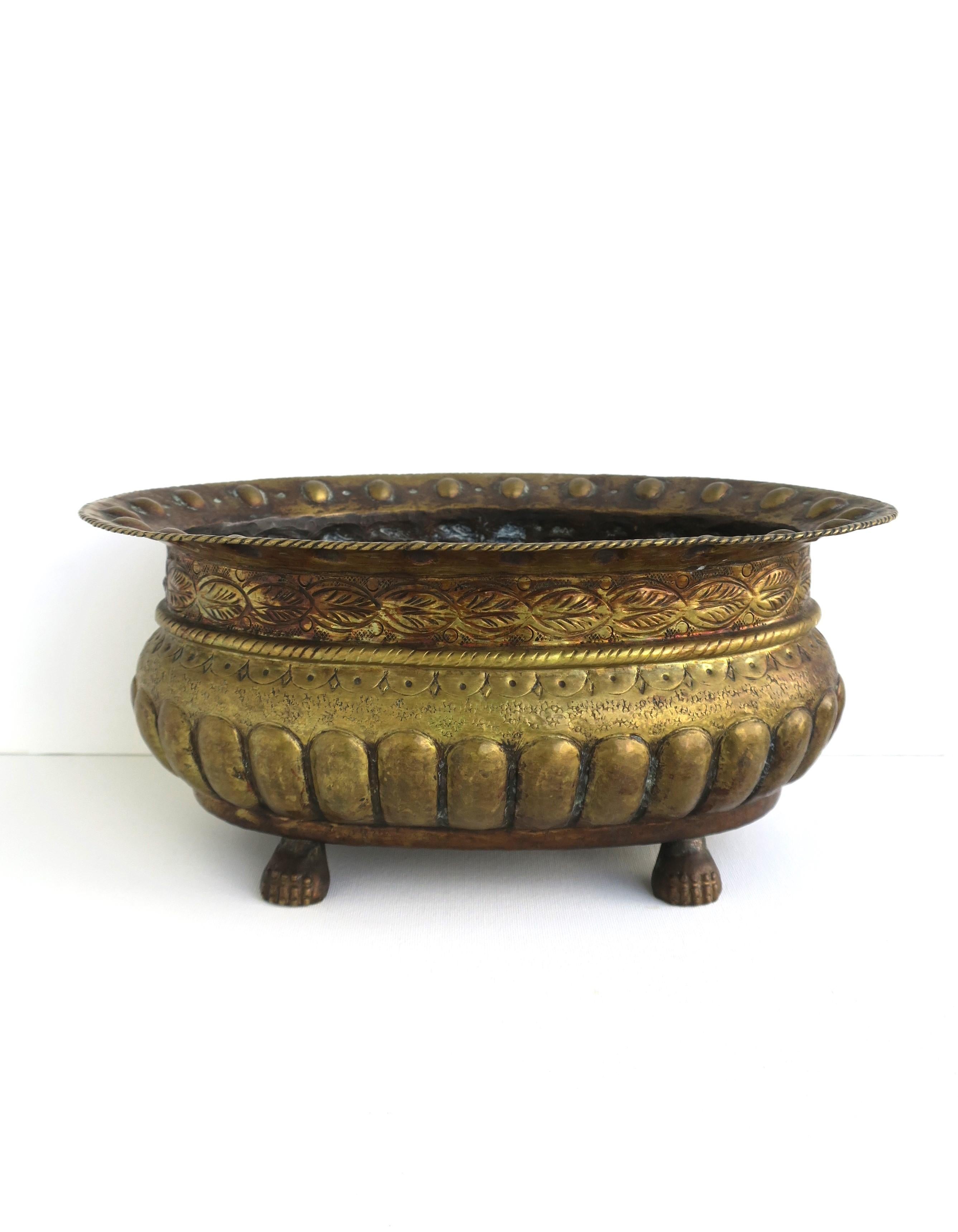 An Italian brass flower or plant pot planter holder cachepot jardiniere with lion paw feet, in the Empire style, circa 20th-century, Italy. A great piece with a repousse and hammered design, finished with lion paw feet. Perfect to hold and display