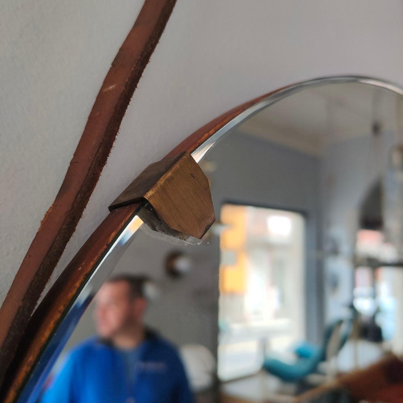 Élégant miroir mural rond avec un cadre en laiton raffiné et une sangle en cuir, conçu dans le style d'Ico Parisi, l'un des designers italiens modernes du milieu du siècle les plus influents. Ce miroir dégage une sophistication intemporelle, alliant