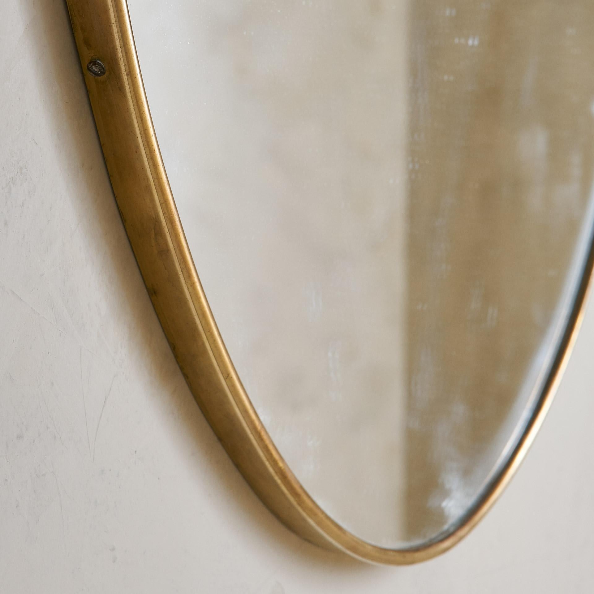 A vintage Italian brass mirror in the shape of a shield. Unlacquered brass + original glass.