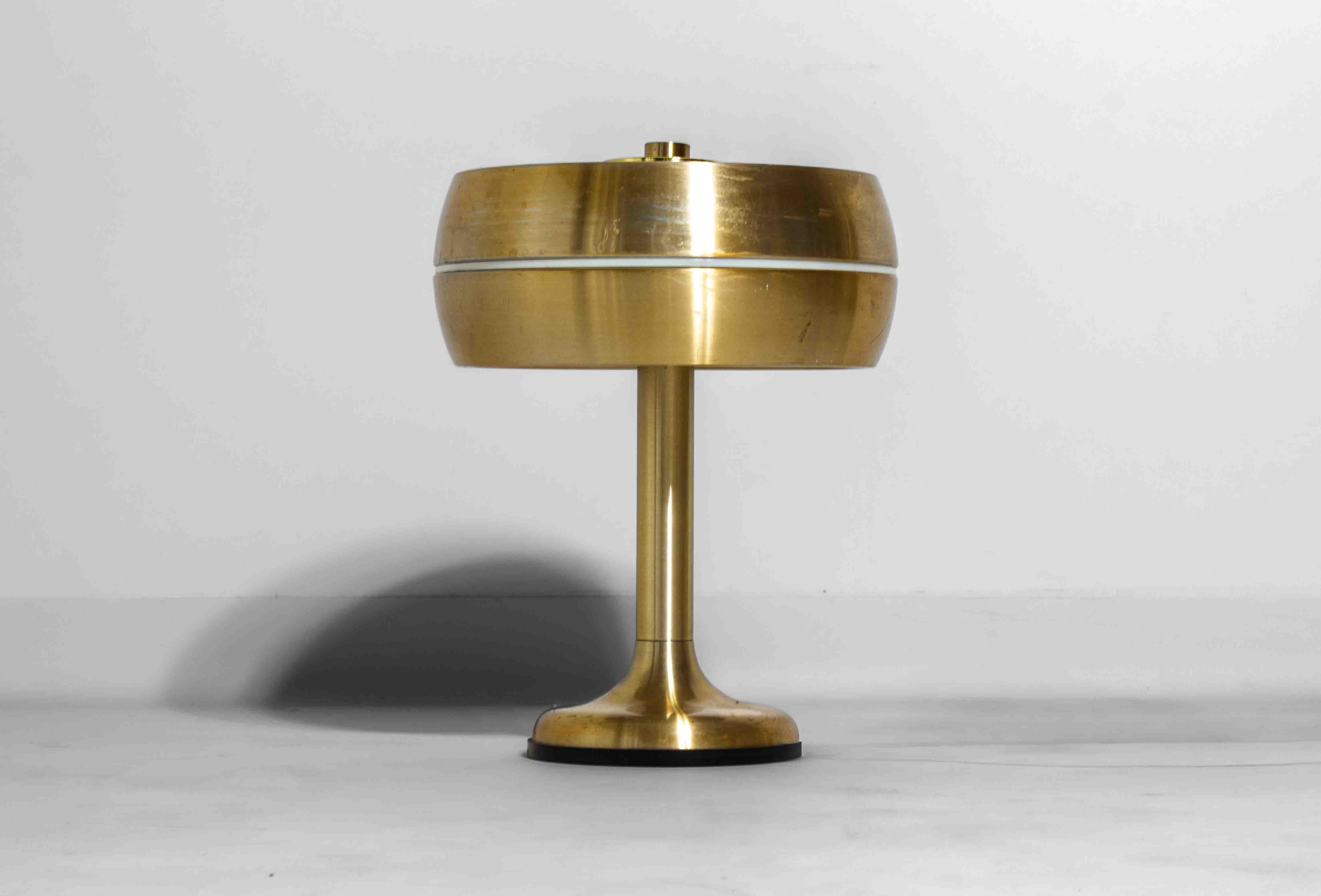 Elegante lámpara italiana de sobremesa o escritorio de los años 60, revestida totalmente de latón cepillado. La pantalla redonda se levanta ligeramente en el centro para dejar escapar la luz a través de la estrecha hendidura de su borde, creando un