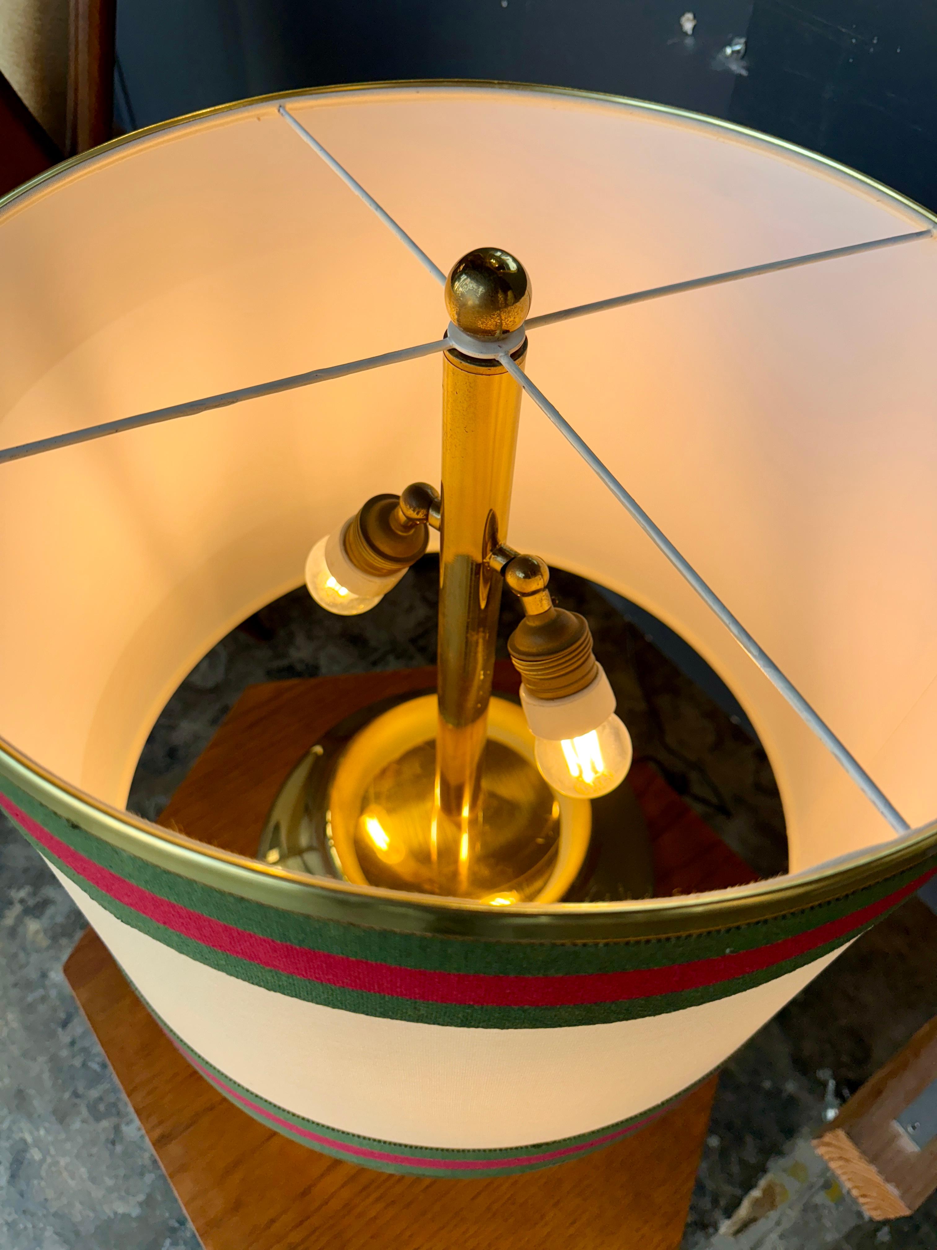 Una raffinata lampada da tavolo italiana che incarna l'eleganza del design di metà secolo. La base, realizzata in ottone massiccio lucidato, offre una calda lucentezza dorata che riflette magnificamente la luce. Il paralume cilindrico in tela, color